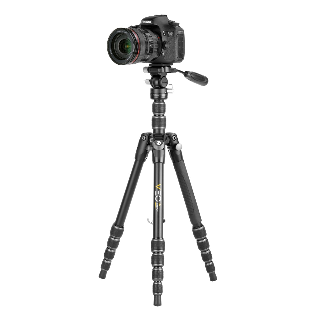 Una cámara Canon DSLR negra está montada en un trípode negro. El trípode tiene tres patas y secciones ajustables. El fondo es blanco.