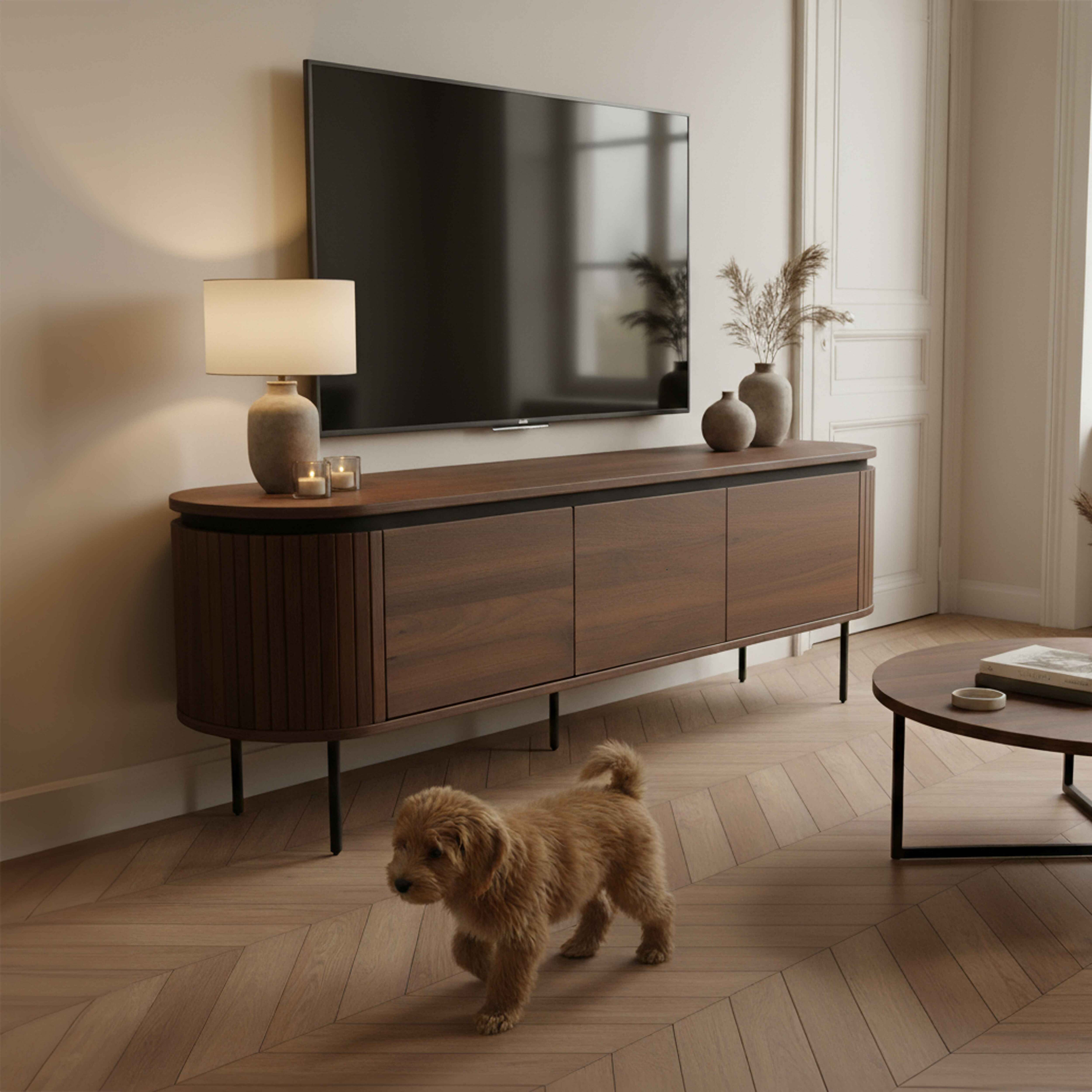 Ein Wohnzimmer mit Fernseher, Holzmöbeln, Hund und rundem Tisch. Warme Beleuchtung und neutrale Farbpalette.