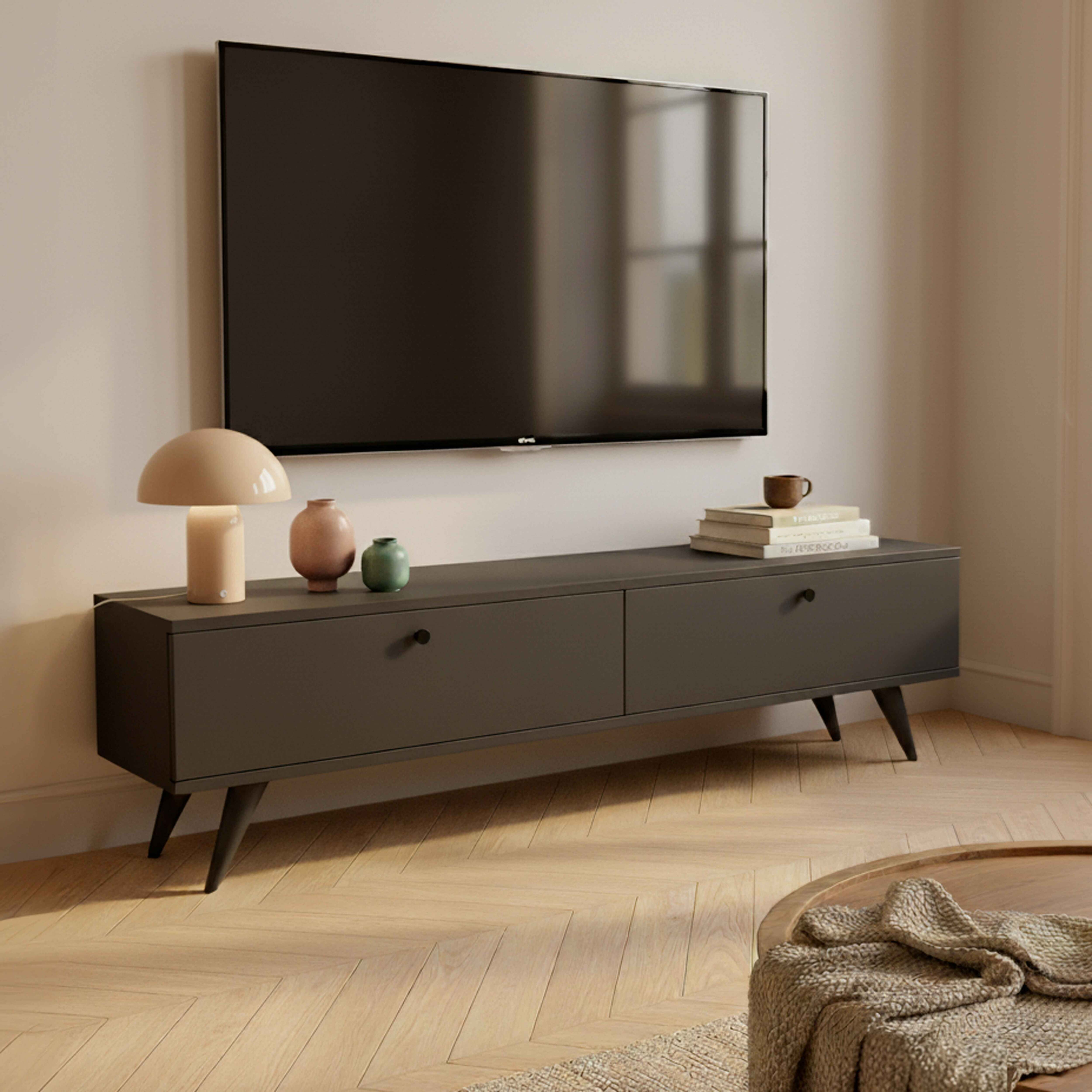 Moderne Wohnzimmereinrichtung mit Fernseher, niedrigem Schrank und Dekorationsartikeln. Ein Couchtisch im Vordergrund.