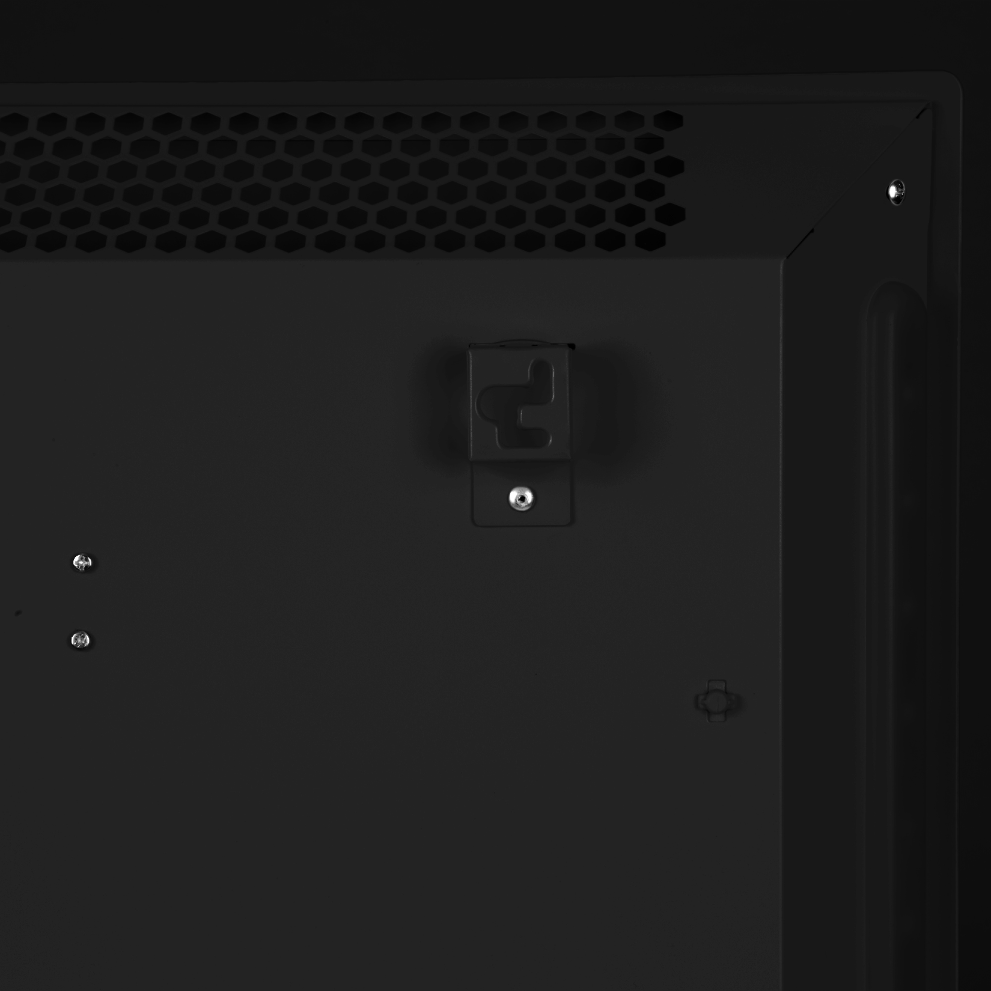 Primer plano de un panel metálico negro con una malla de panal, un soporte y varios tornillos. El panel tiene un acabado mate.