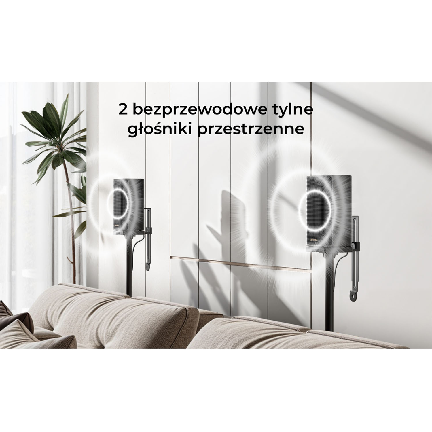 Dwa bezprzewodowe tylne głośniki surround są zamontowane na czarnych stojakach, za beżową sofą. Po lewej roślina. Biała ściana w tle.