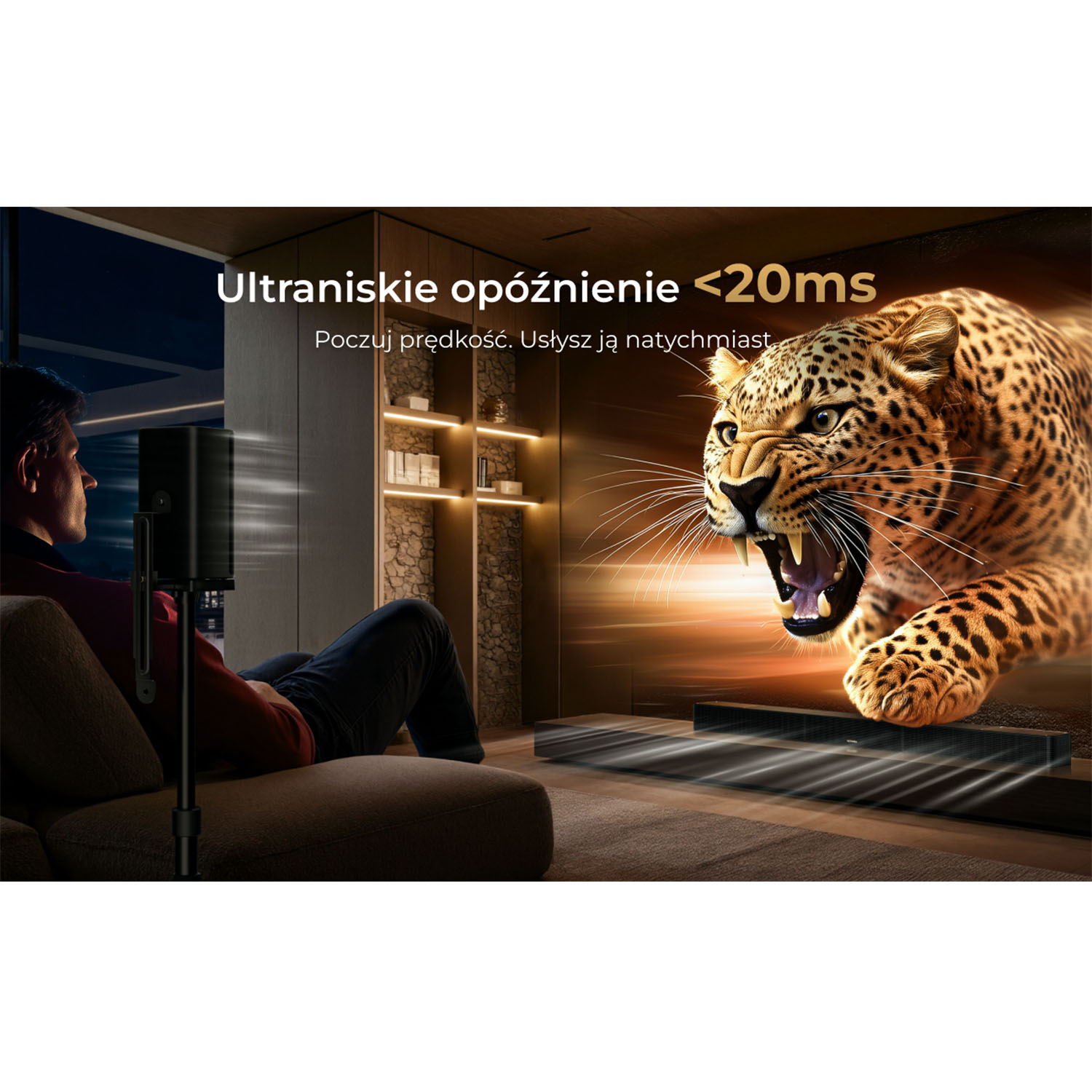 Mężczyzna ogląda ryczącego lamparta na ekranie telewizora. Na ekranie widać wyskakującego lamparta. Pod ekranem znajduje się głośnik.