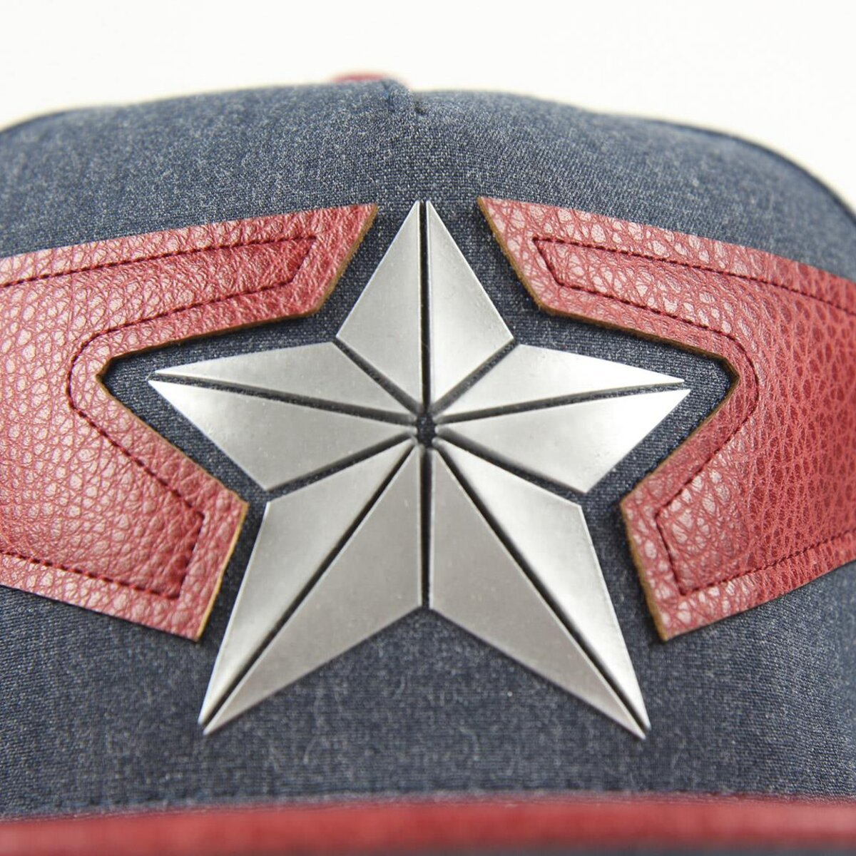 Primer plano de una gorra con un emblema de estrella plateada sobre una superficie azul, con detalles de cuero rojo.