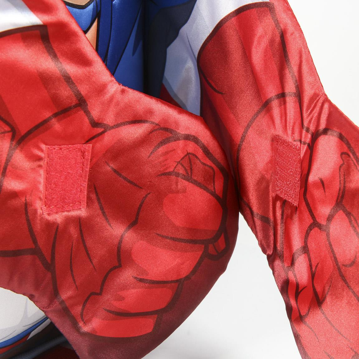 Primer plano de un disfraz de superhéroe rojo. Manos con contornos negros y parches de velcro rojos. Tela azul y blanca en el fondo.