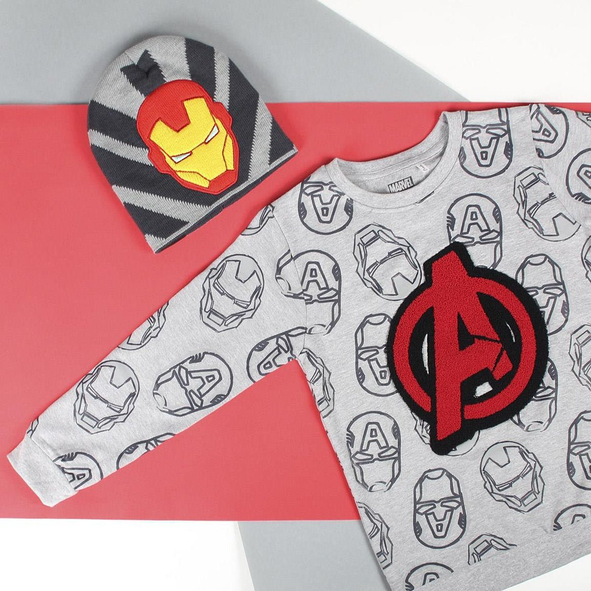 Camiseta y gorro grises con logotipos de Iron Man y Vengadores. Fondo rojo y gris con logo de Marvel.