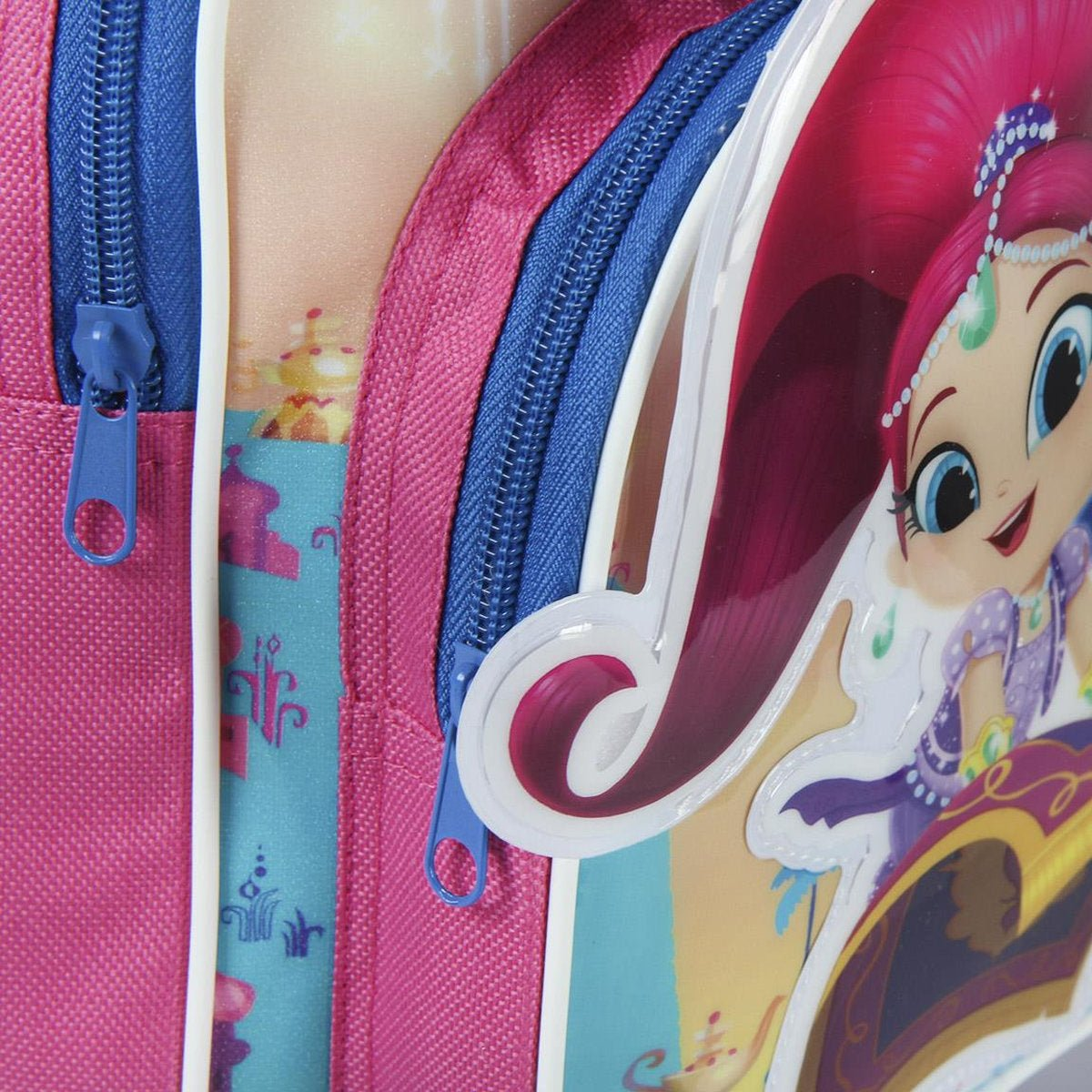 Primer plano de una mochila rosa con cremalleras azules y un personaje de dibujos animados. El personaje tiene pelo rojo y ojos grandes.