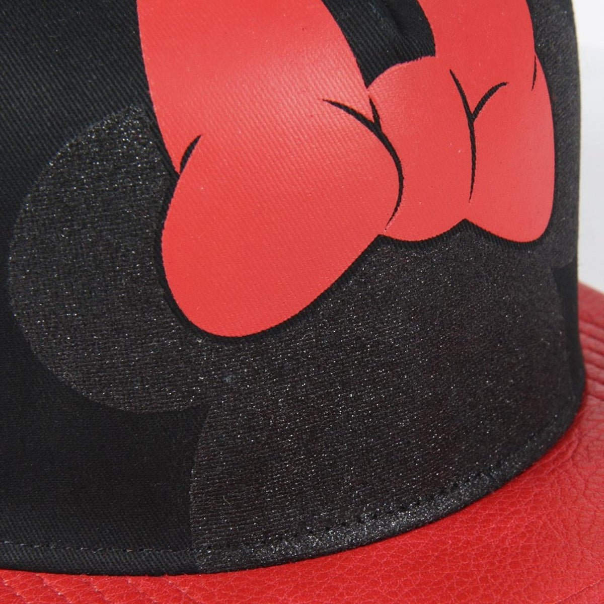 Primer plano de una gorra de béisbol negra con un diseño de puño rojo estilizado en la parte superior. La visera es de cuero rojo. El fondo está borroso.