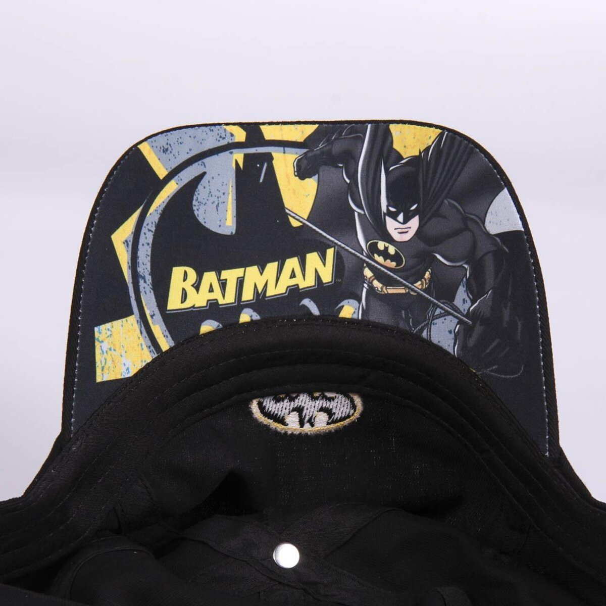 Una gorra negra de Batman. La gorra tiene el logo y la imagen de Batman. El fondo es blanco.