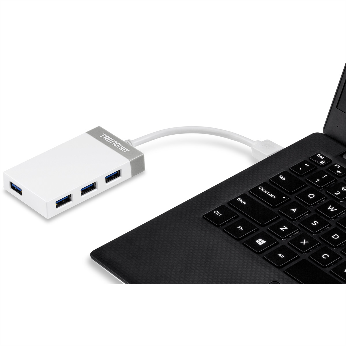 Ein weißer TRENDnet USB-Hub ist mit einem Laptop mit schwarzer Tastatur verbunden. Der Hub hat vier USB-Anschlüsse.