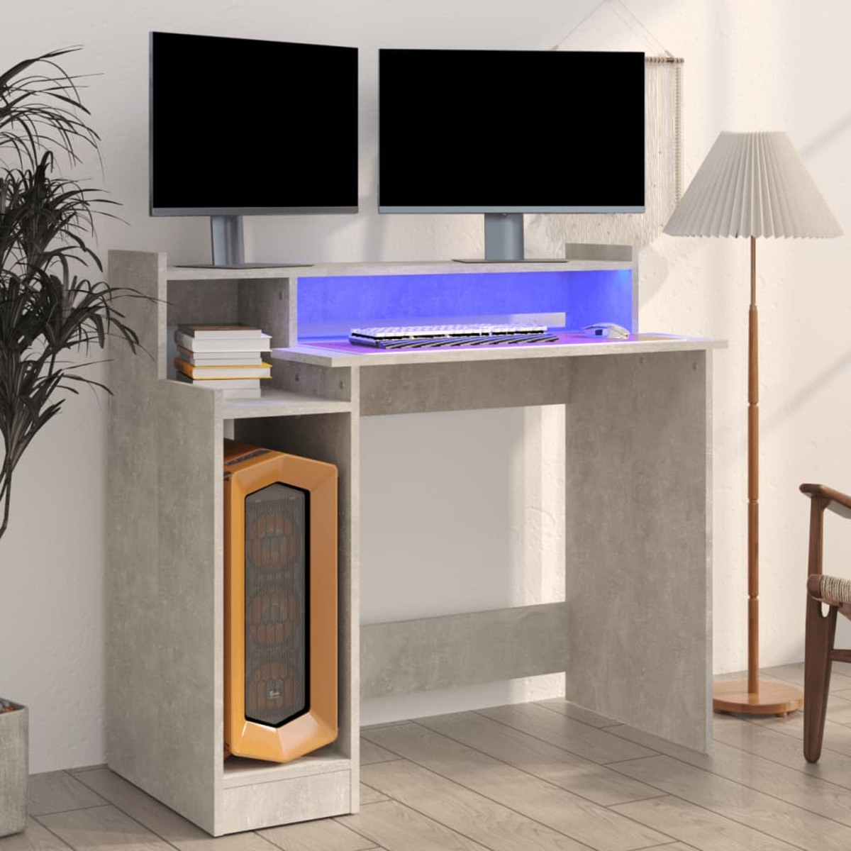 Ein Computertisch mit zwei Monitoren, einem PC-Gehäuse und einer Tastatur. Im Hintergrund befinden sich eine Lampe und eine Pflanze.