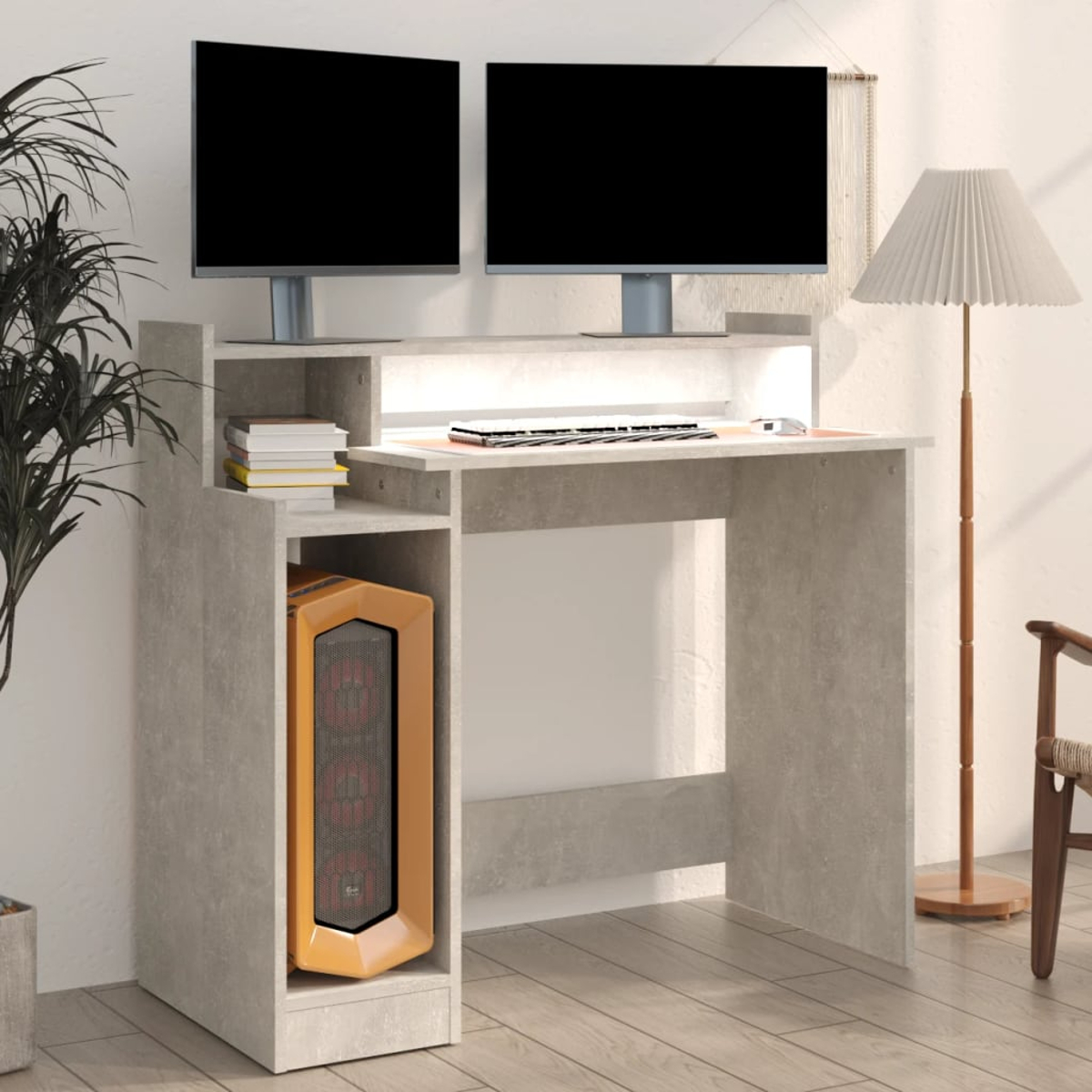 Ein Computertisch mit zwei Monitoren, einem Computerturm und einer Lampe. Links ist eine Pflanze und rechts ein Stuhl.