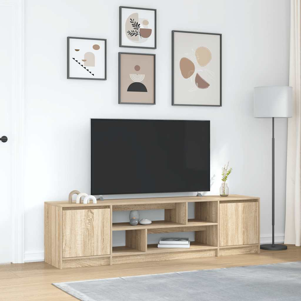 Ein Wohnzimmer mit Fernseher auf einem Holzschrank. Kunst an der Wand. Eine Lampe steht rechts. Ein Teppich auf dem Boden.