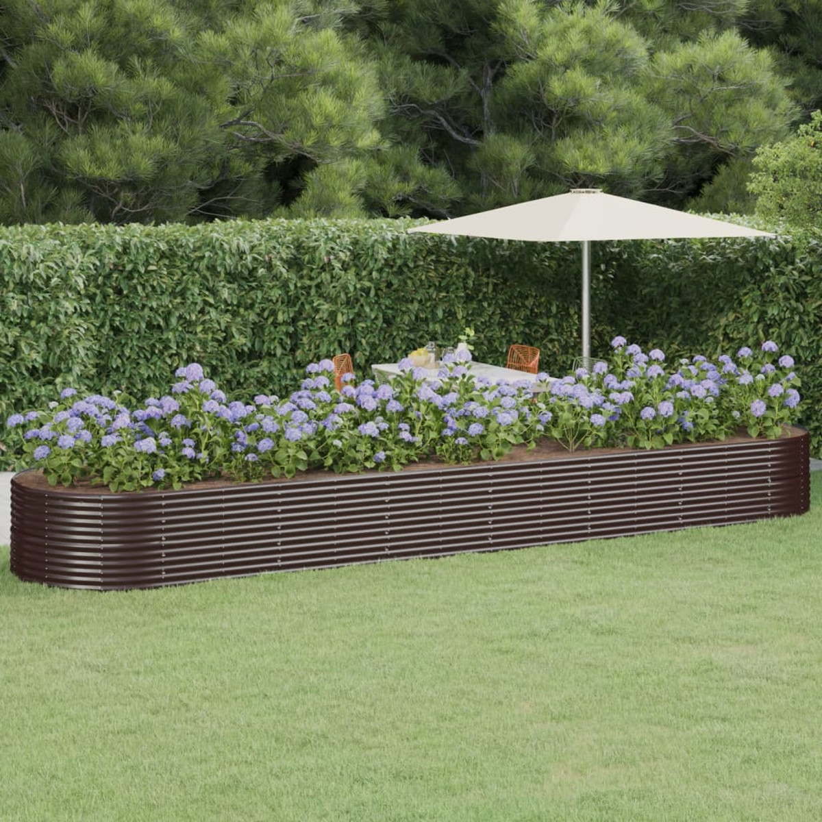 Eine Gartenszene mit einer braunen, gewellten Pflanzkasten mit blauen Blumen. Ein Tisch mit Stühlen und ein Sonnenschirm sind sichtbar.