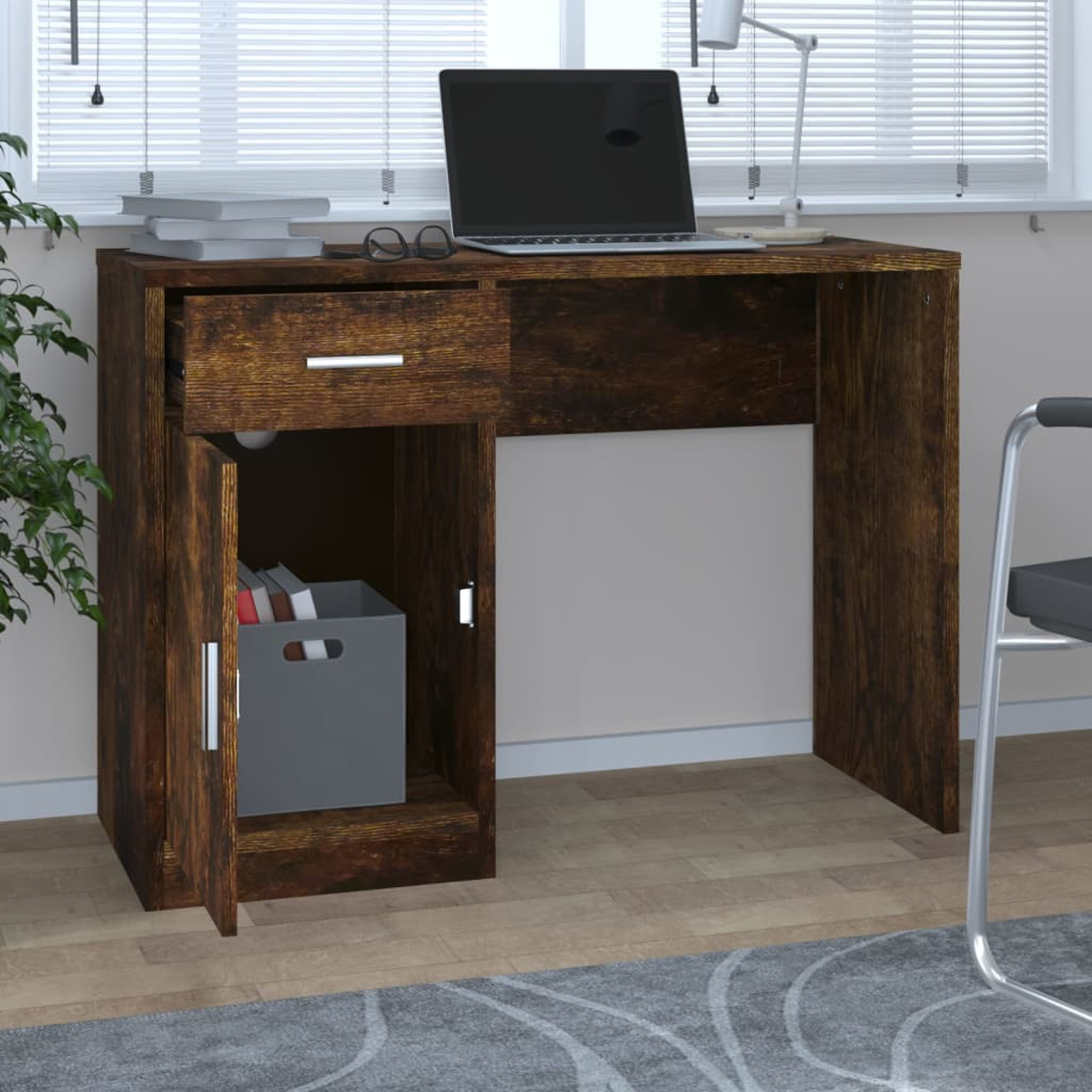 Ein Holzschreibtisch mit Laptop, Schublade, offenem Schrank mit grauer Box und Büchern. Auf dem Schreibtisch liegt eine Brille. Im Hintergrund befindet sich ein Fenster.