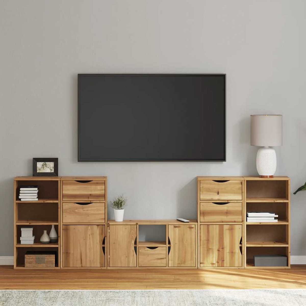 Wohnzimmer mit Holzmöbeln und großem Fernseher. Regale, Schubladen, Schränke und eine Lampe sind sichtbar. Eine kleine Pflanze und eine Fernbedienung sind vorhanden.