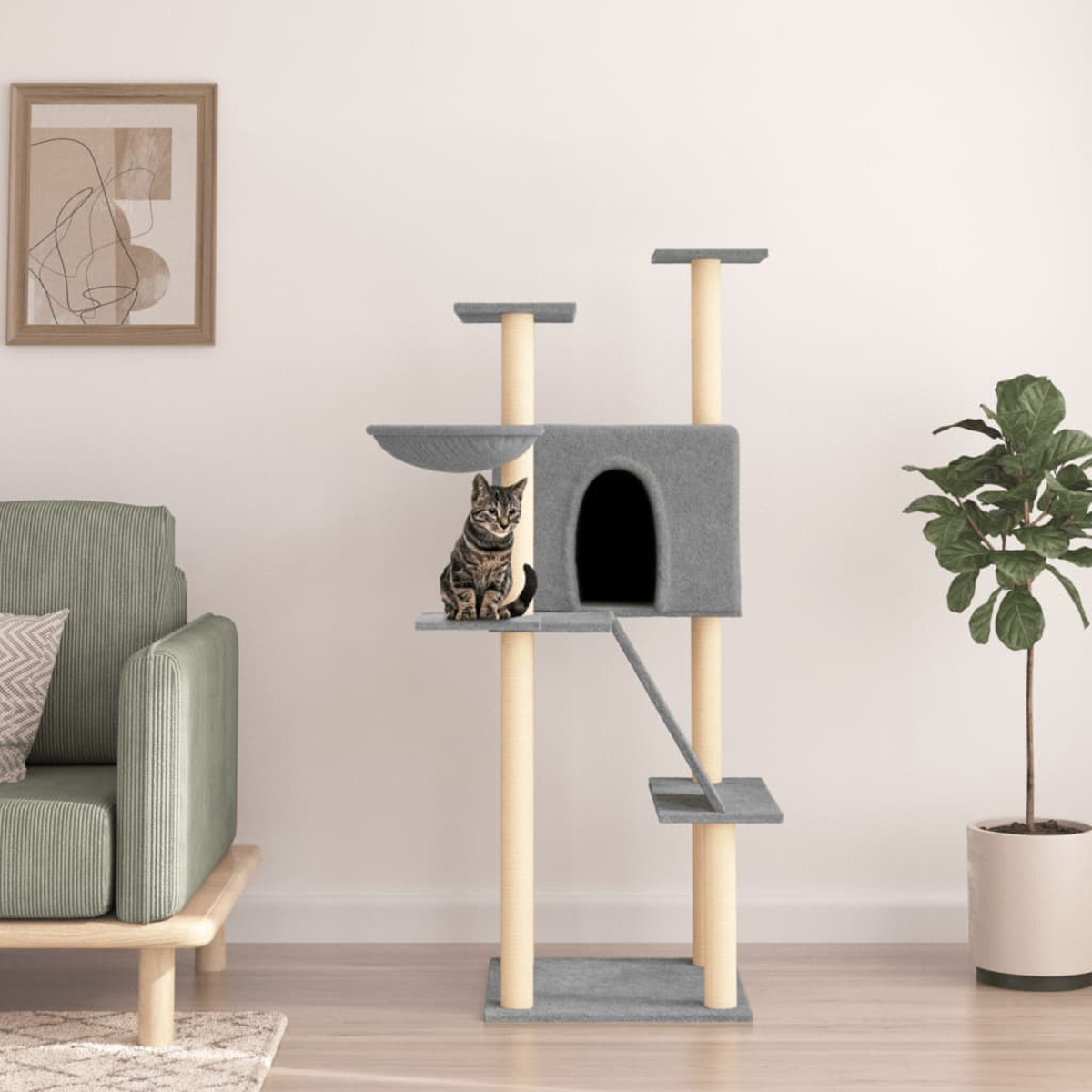 Eine Katze sitzt auf einem grauen Kratzbaum. Der Baum hat Ebenen und ein Katzenhaus. Eine grüne Couch und eine Pflanze sind im Hintergrund.