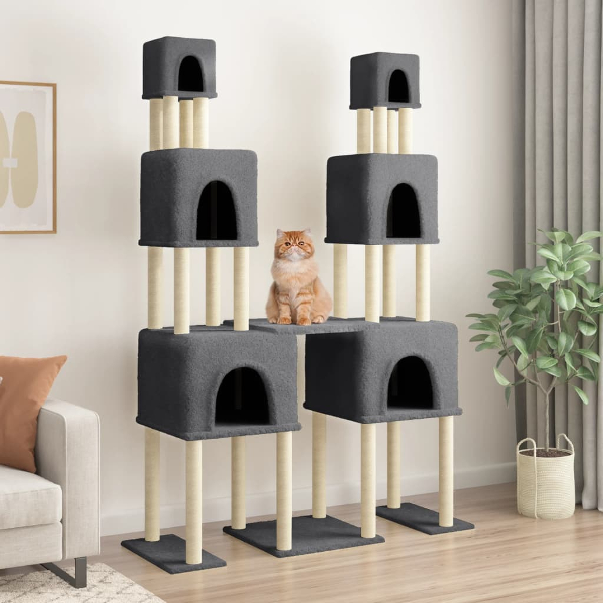Eine orange Katze sitzt auf einem grauen Kratzbaum. Der Baum hat mehrere Ebenen und Höhlen. Im Hintergrund sind ein Sofa und eine Pflanze.