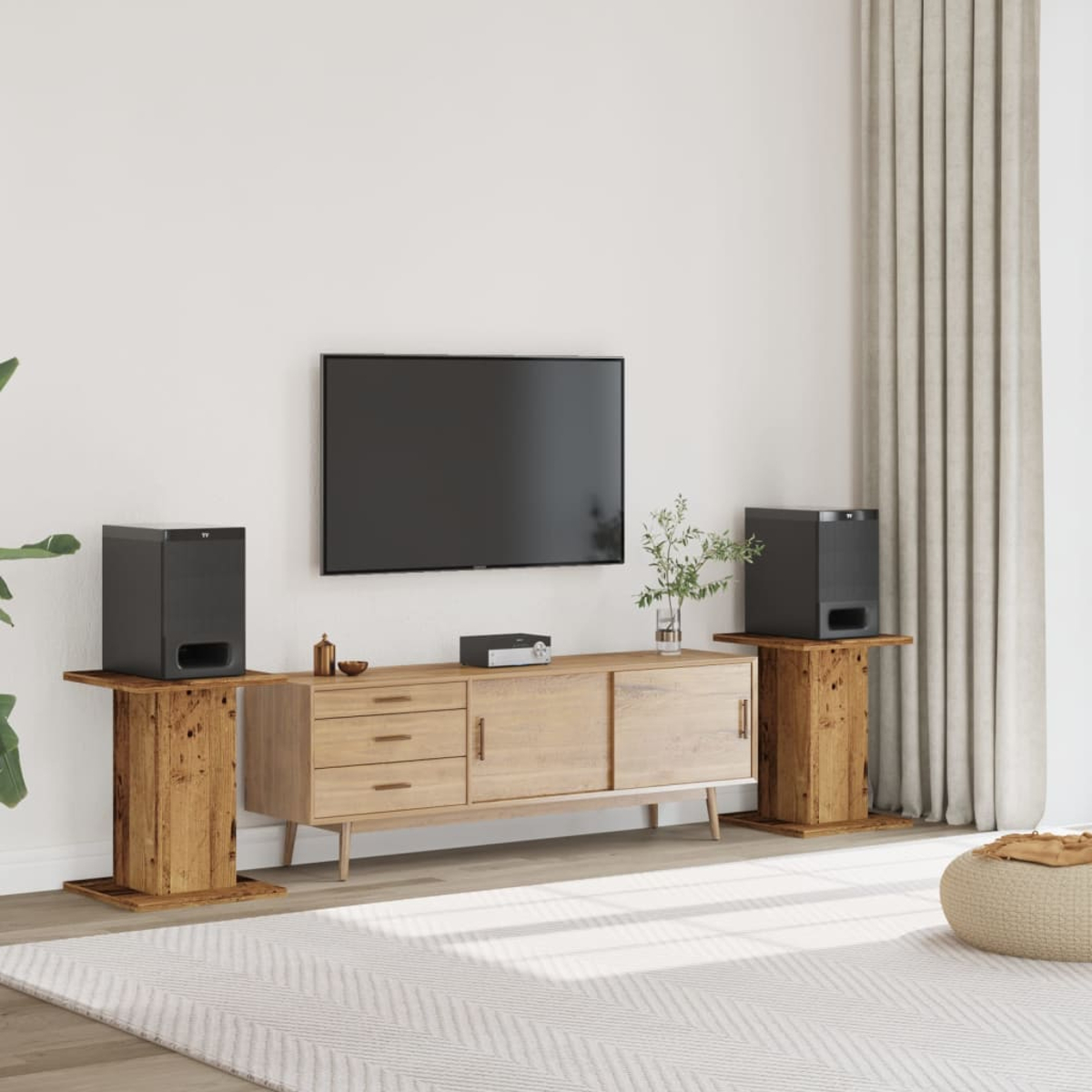 Wohnzimmer mit Fernseher, Lautsprechern und Holzmöbeln. Ein Teppich und ein gemusterter Vorhang sind ebenfalls sichtbar.