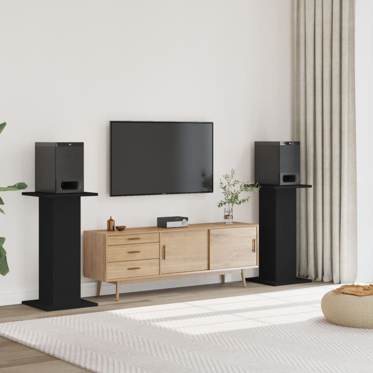 Ein Wohnzimmer mit Fernseher, Lautsprechern und einem Holzschrank. Es gibt einen Teppich, Vorhänge und einen dekorativen Pouf.