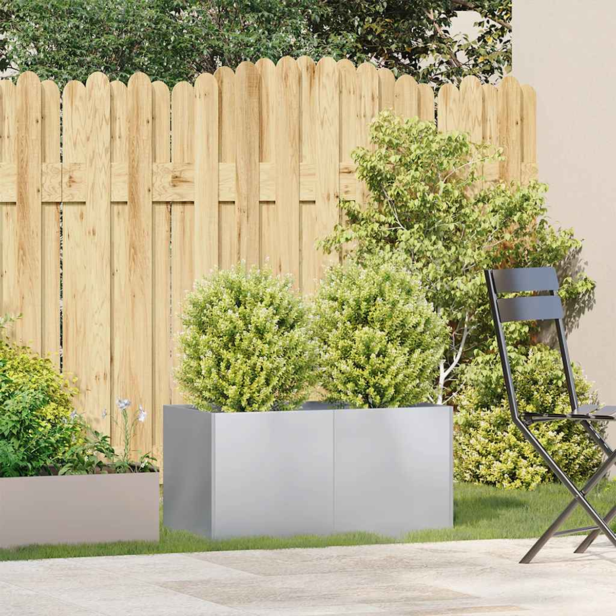 Scena di giardino con una staccionata in legno, fioriere con cespugli verdi e una sedia nera. Lo sfondo ha più verde.