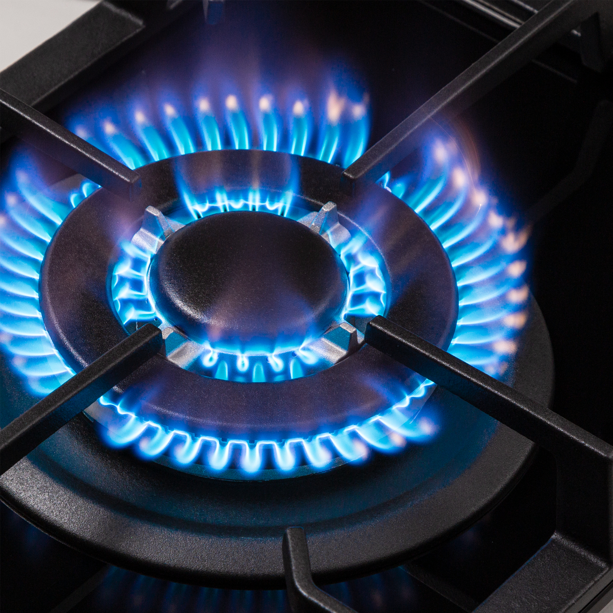 Primo piano di un bruciatore con fiamme blu brillante. Il bruciatore è nero, con un design circolare.