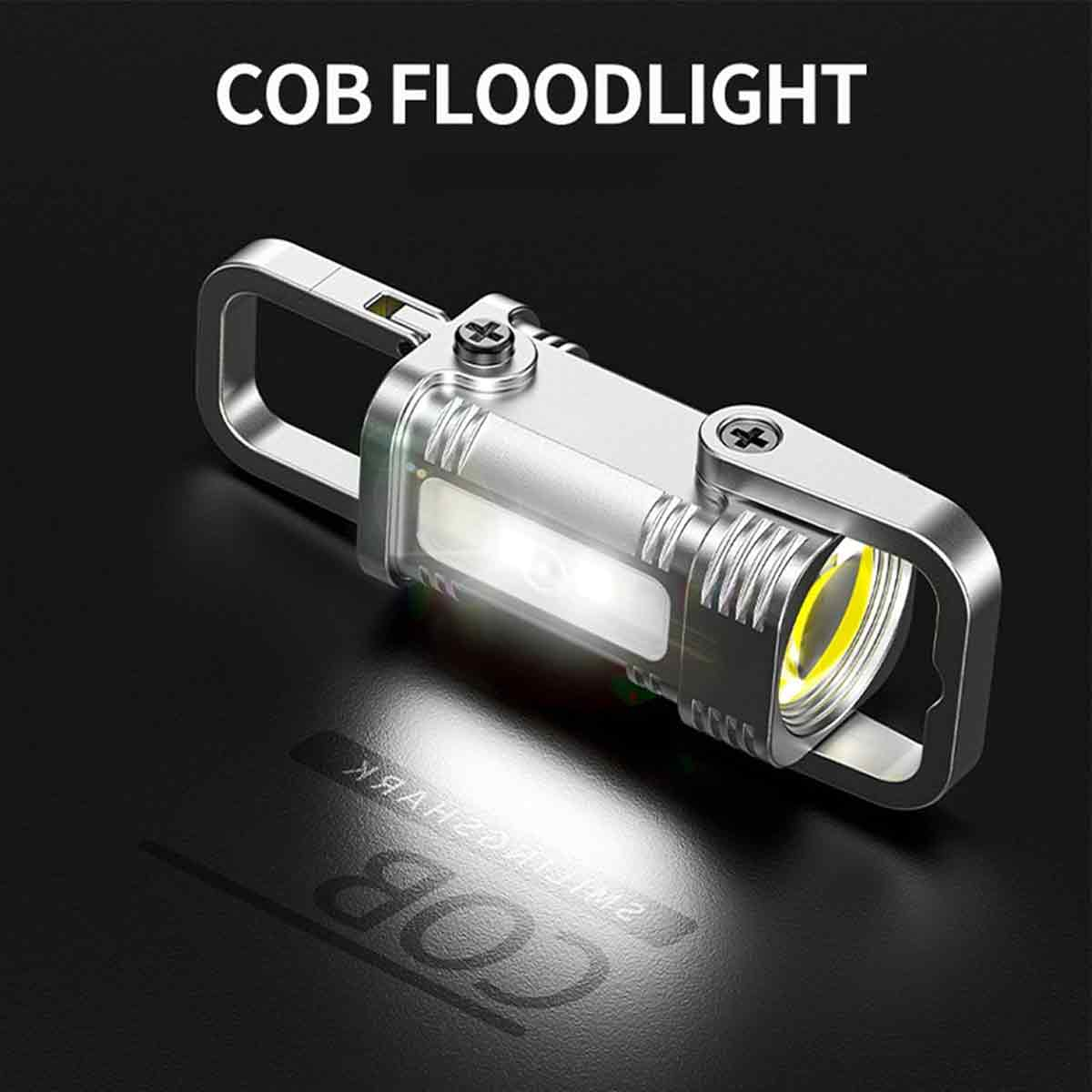 Ein silbernes COB-Flutlicht liegt auf einer dunklen Oberfläche. Das Licht ist eingeschaltet und beleuchtet die Oberfläche. Der Text 'COB FLOODLIGHT' steht oben.
