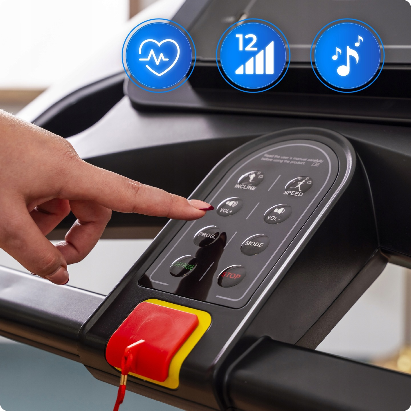 Ręka naciska przycisk na panelu sterowania bieżni. Niebieskie ikony tętna, sygnału i muzyki znajdują się powyżej.