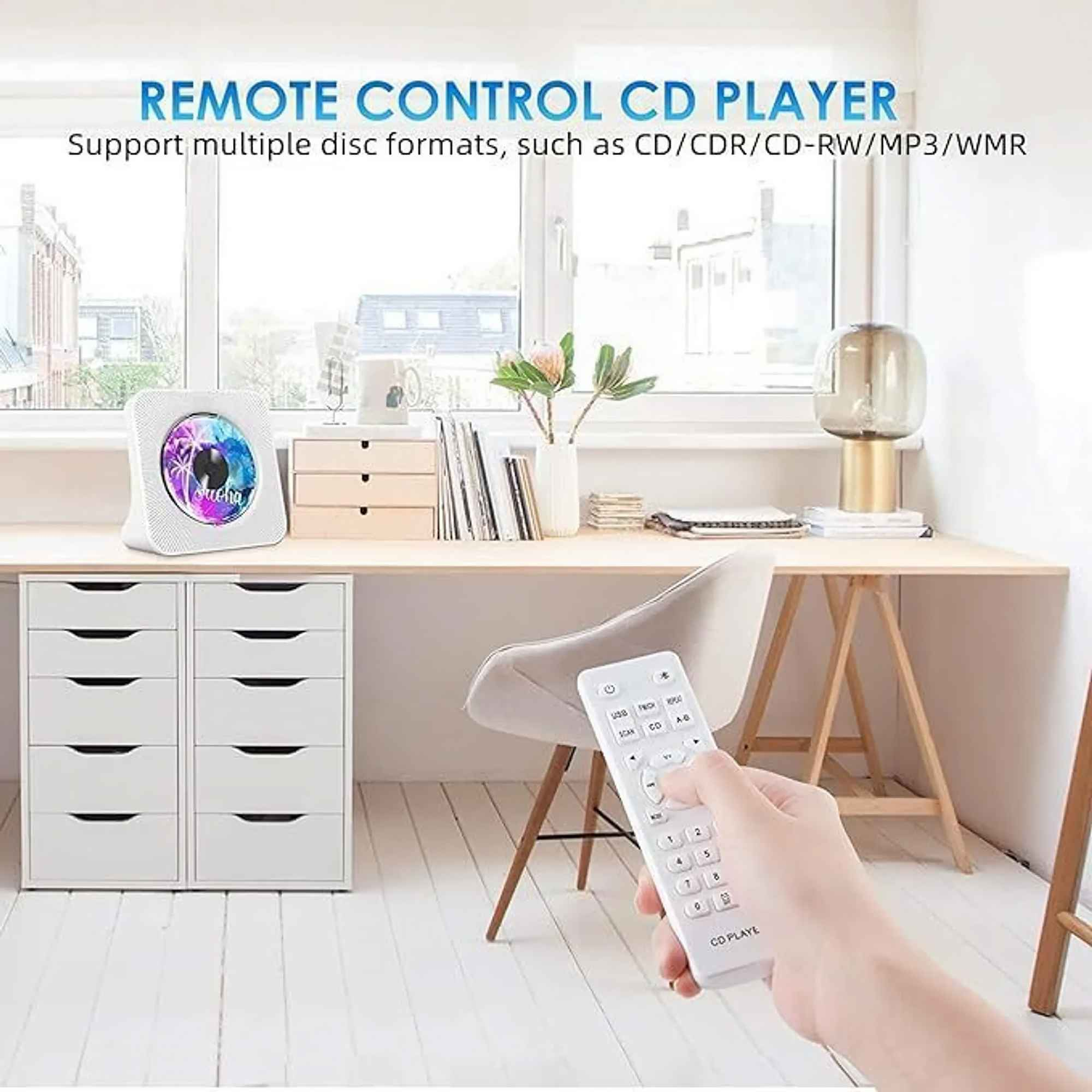 Ein weißer CD-Player mit Fernbedienung steht auf einem Schreibtisch. Hand hält die Fernbedienung. Ein Schubladenschrank befindet sich links.