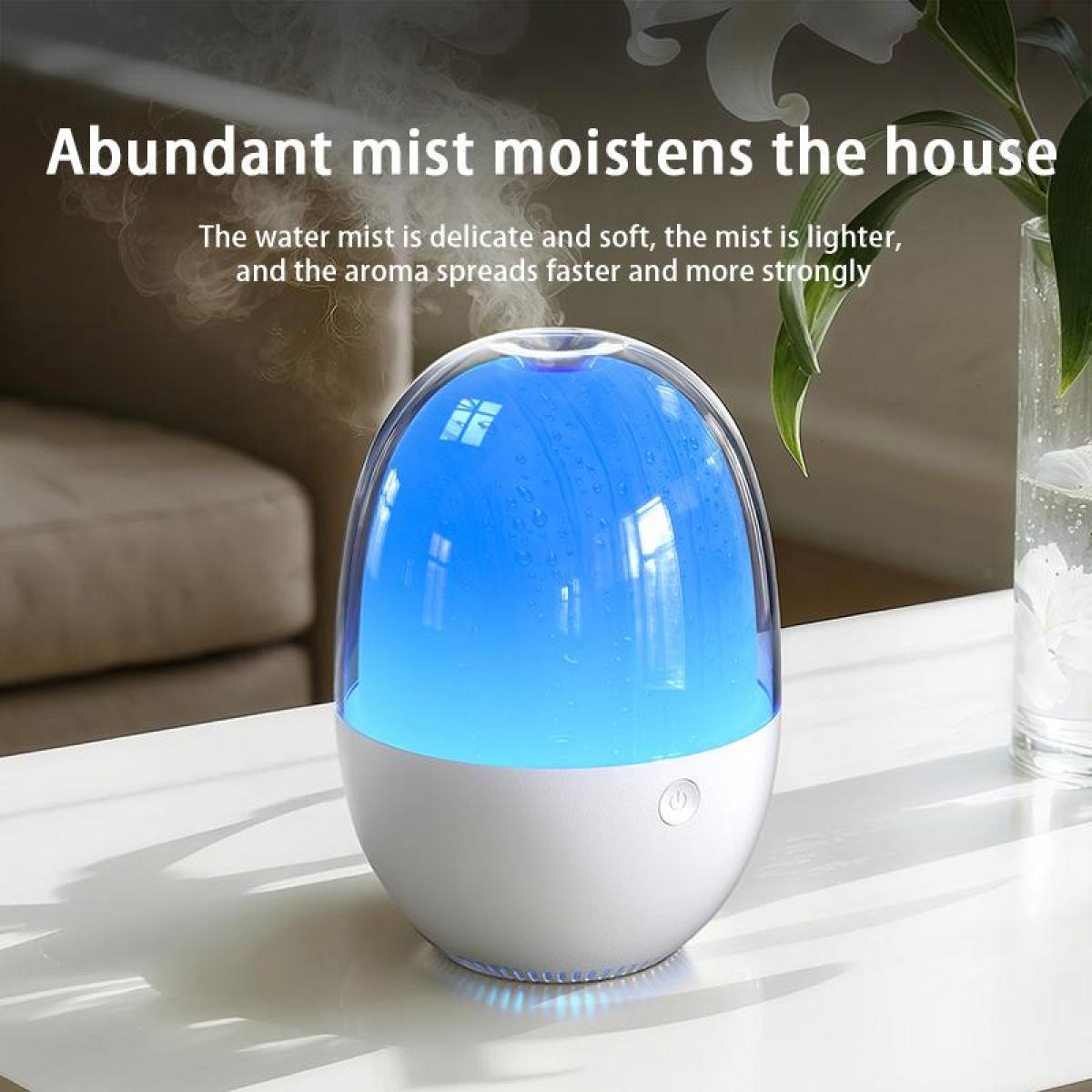 Ein weiß-blauer Luftbefeuchter auf einem weißen Tisch. Nebel steigt auf. Im Hintergrund eine Vase mit Blumen.