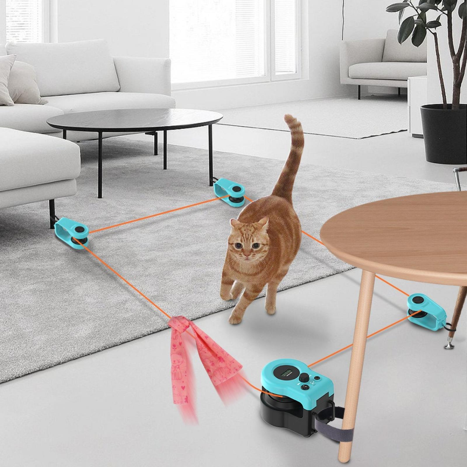 Eine orangefarbene Katze spielt mit einem Spielzeug. Das Spielzeug ist durch orangefarbene Schnüre mit blauen Geräten verbunden.