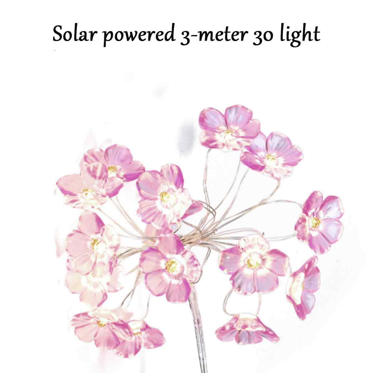 Nahaufnahme von solarbetriebenen Blumenlichtern, rosa Blütenblätter mit gelben Zentren auf weißem Hintergrund, dekorativ.