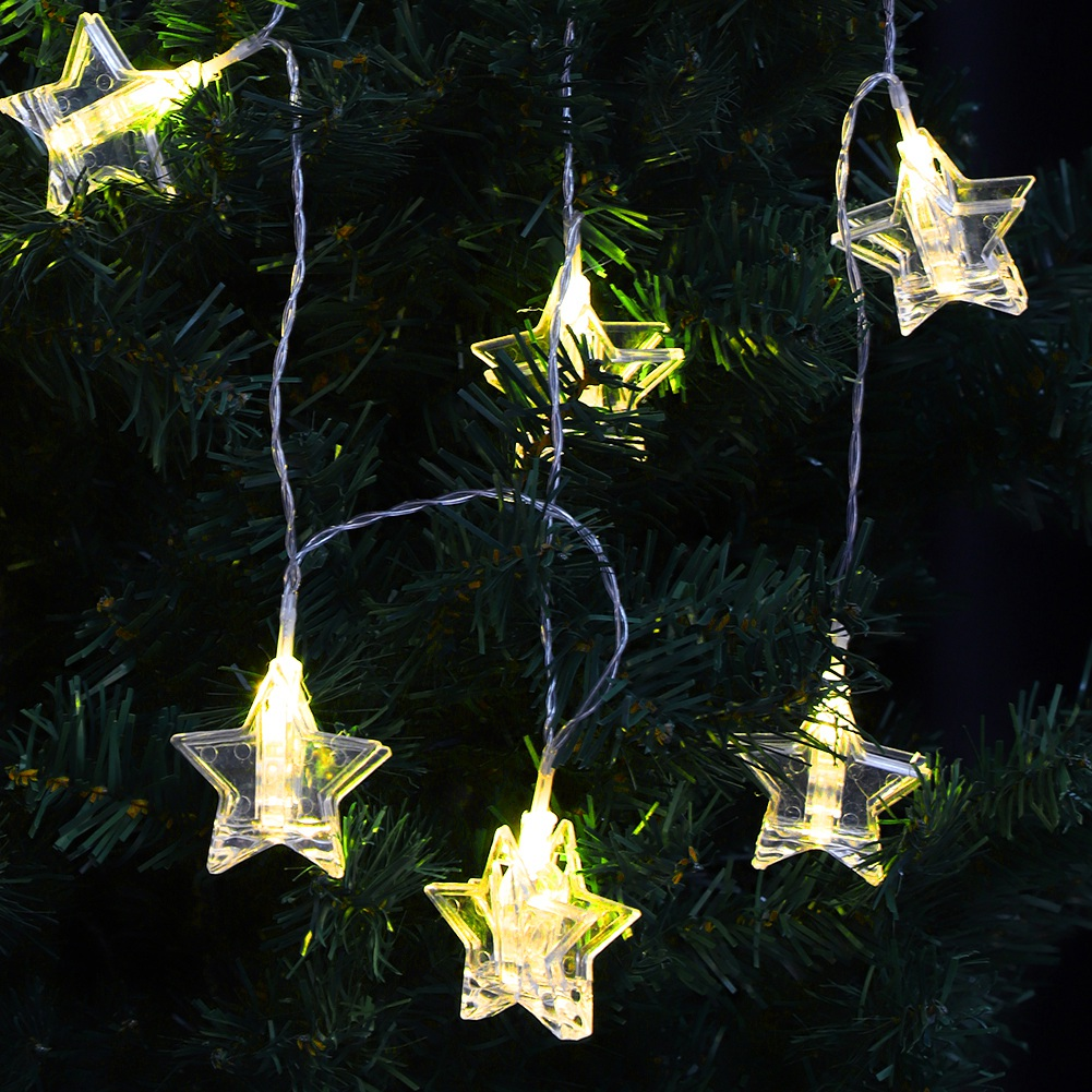 Eine Lichterkette mit sternförmigen Lichtern an einem Weihnachtsbaum. Die Lichter leuchten, der Baum ist grün mit dunklem Hintergrund.