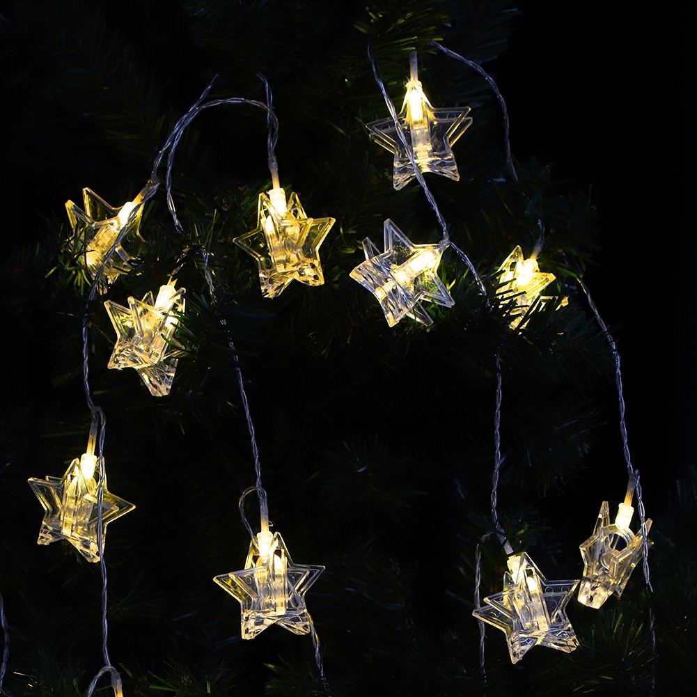 Lichterkette mit sternförmigen, klaren Lichtern. Die Lichter befinden sich vor einem dunkelgrünen Hintergrund, wahrscheinlich einem Weihnachtsbaum.