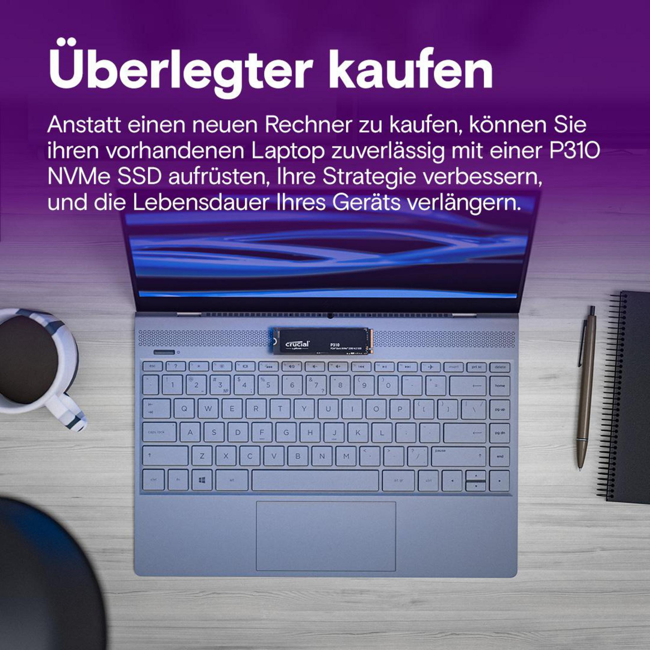 Laptop z dyskiem SSD Crucial P310 na biurku. Widoczna klawiatura. Obecny jest również kubek kawy i notatnik.