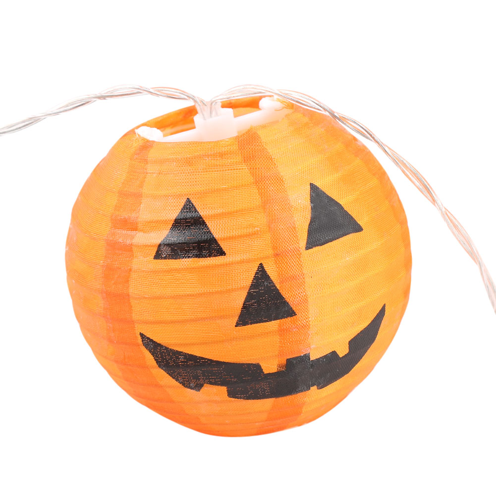 Eine orangefarbene, kürbisförmige Halloween-Laterne mit einem lächelnden Gesicht, schwarzen Merkmalen und dünnen Drahtlichtern.