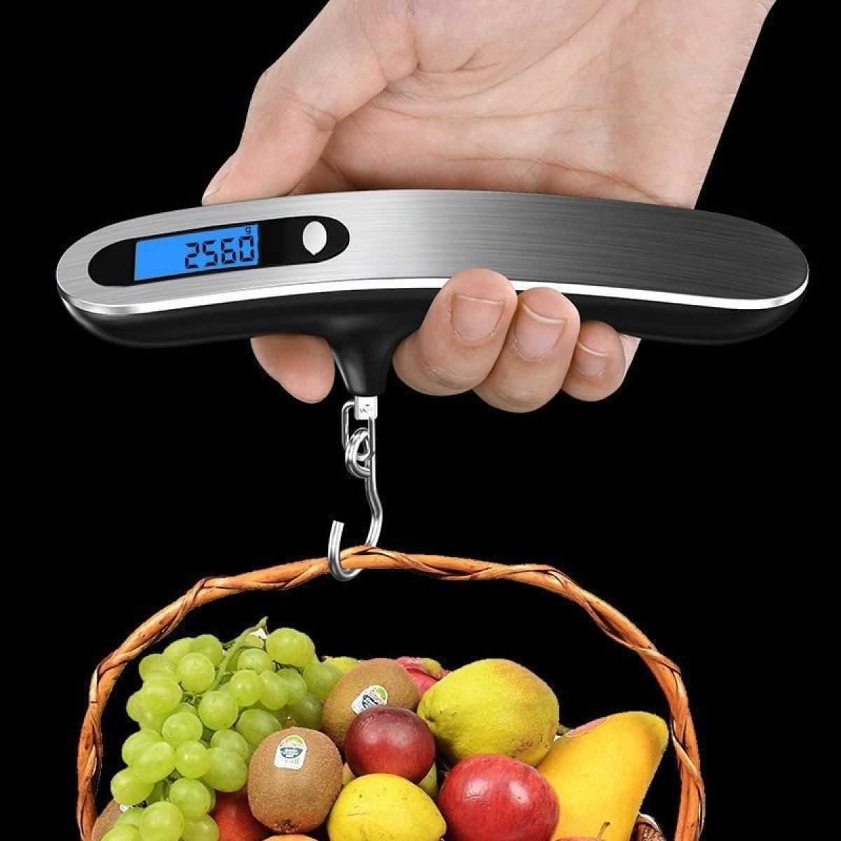 Eine Hand hält eine Digitalwaage, die einen Korb mit Früchten wie Trauben, Äpfeln und Kiwi wiegt. Die Waage zeigt 25,60 an.