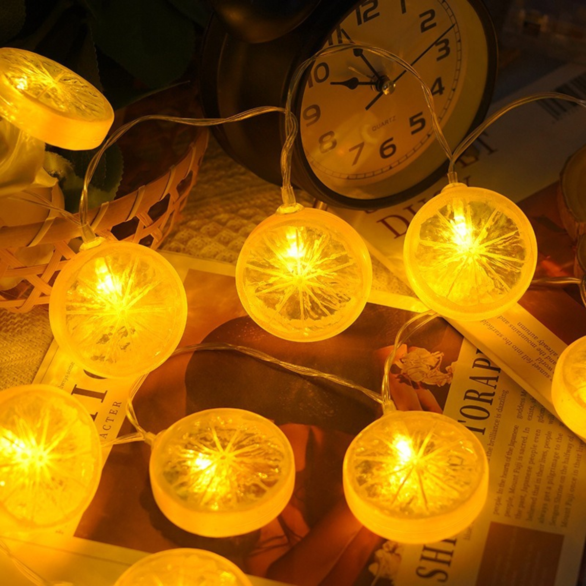 Beleuchtete Lichterketten in Form von Zitronenscheiben. Im Hintergrund eine Uhr mit Text auf der Seite. Die Lichter sind hellgelb.