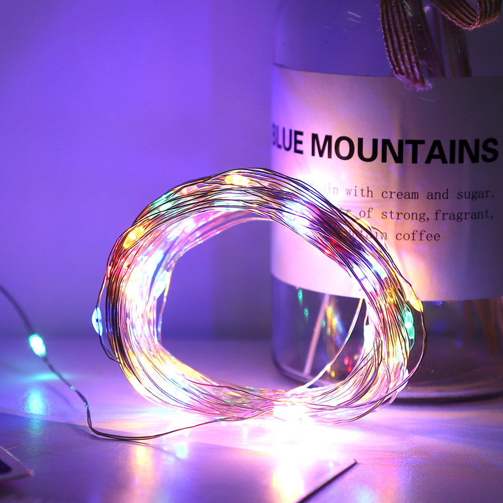 Eine Spule bunter Lichterketten leuchtet hell. Im Hintergrund steht ein Glasgefäß mit der Aufschrift 'Blue Mountains'.