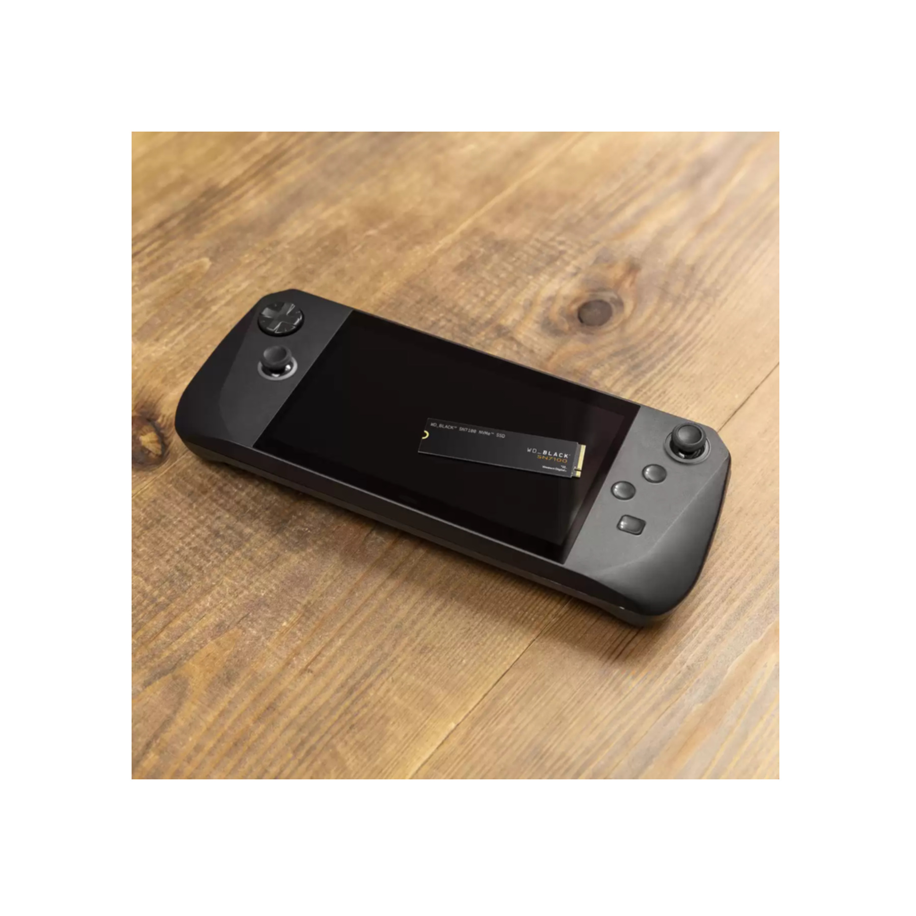 Czarna konsola do gier przenośnych z małym dyskiem SSD na ekranie, na drewnianej powierzchni.