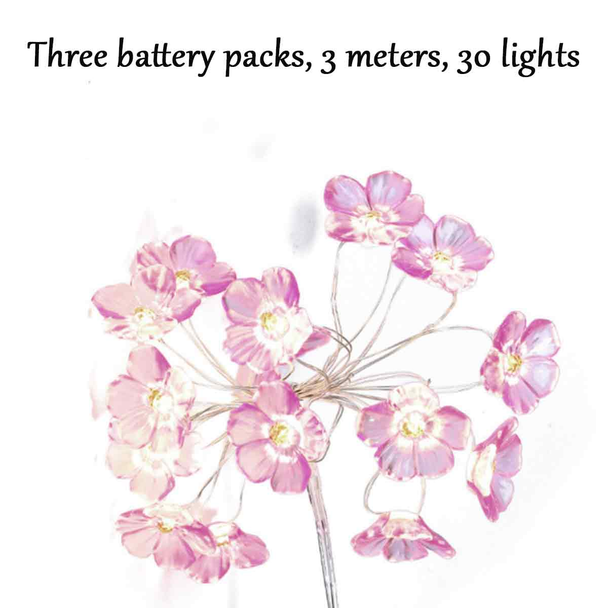 Eine Blumen-Lichterkette mit rosa blütenförmigen Lichtern. Der Hintergrund ist weiß. Der Text oben lautet: Drei Akkus, 3 Meter, 30 Lichter.