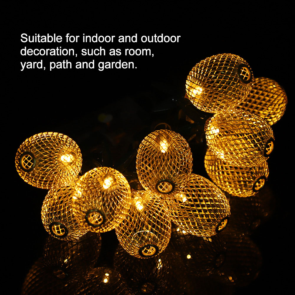 Goldene, kugelförmige Lichterkette. Jedes Licht ist in einem gemusterten Metallkäfig eingeschlossen. Lichter leuchten vor schwarzem Hintergrund.