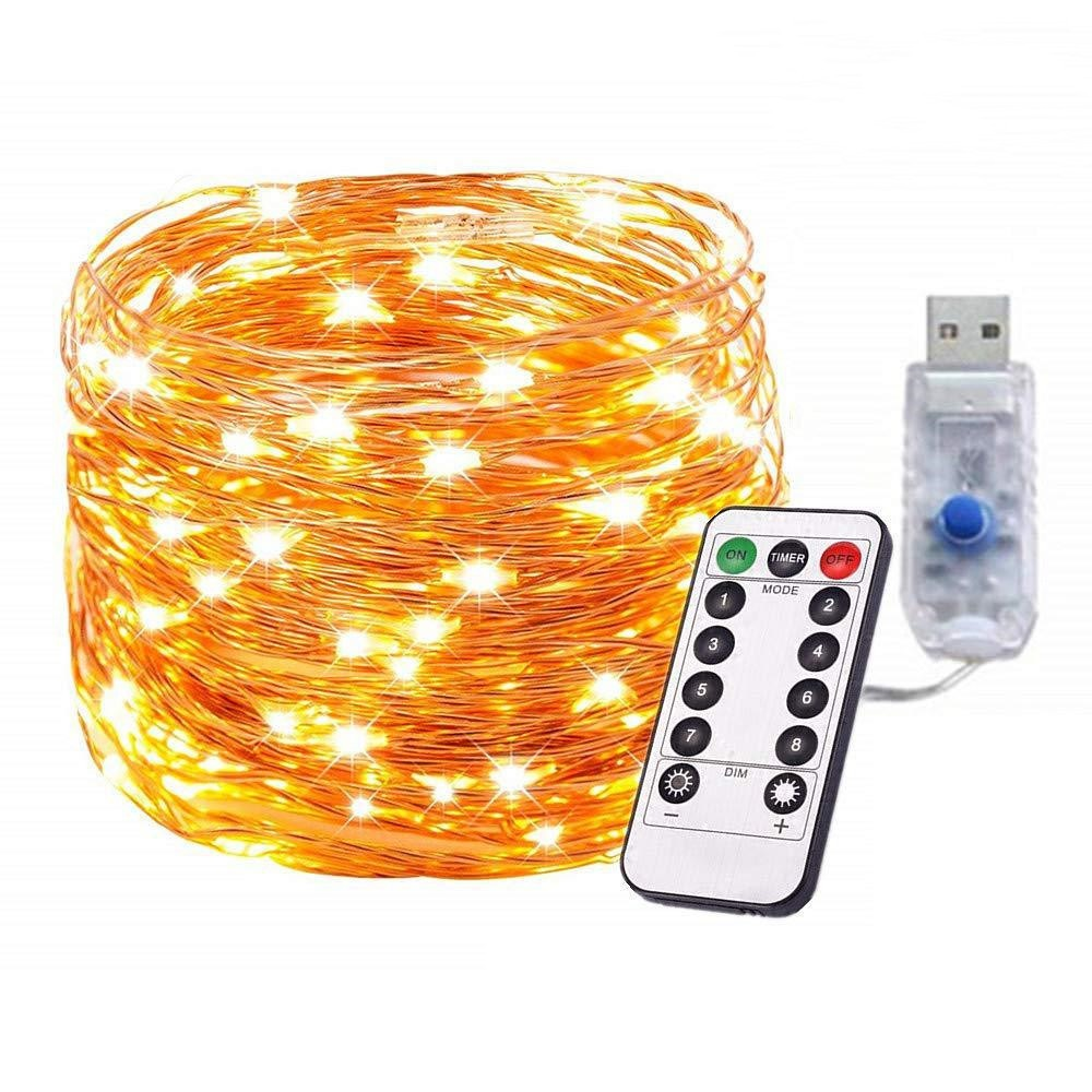 Ein Bündel kupferfarbener LED-Lichterketten, eine Fernbedienung und ein USB-Netzteil auf weißer Oberfläche.