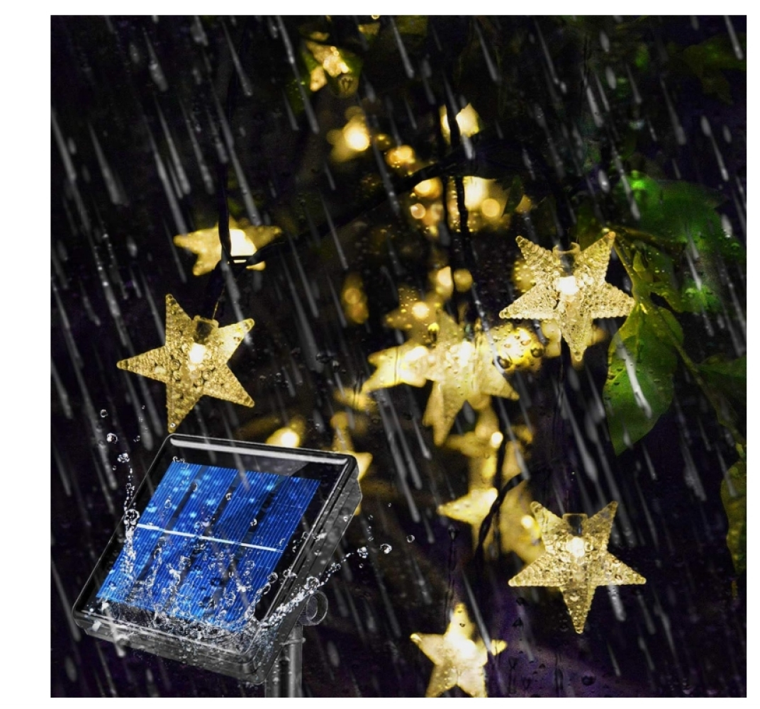 Sternförmige Lichterketten im Regen, betrieben von einem Solarpanel. Gelbe Sterne vor dunklem Hintergrund, Wassertropfen sichtbar.