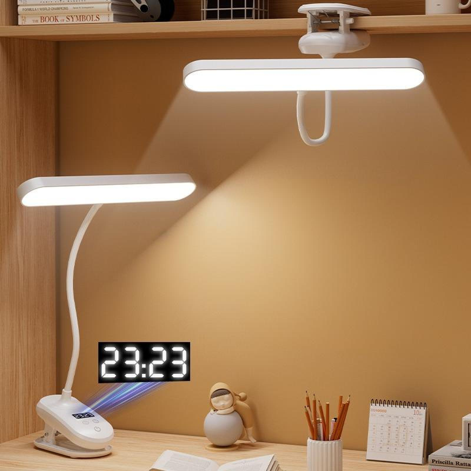 Ein Schreibtisch mit zwei Lampen, einer Digitaluhr mit 23:23, Bleistiften, einem Kalender und einer kleinen Statue.