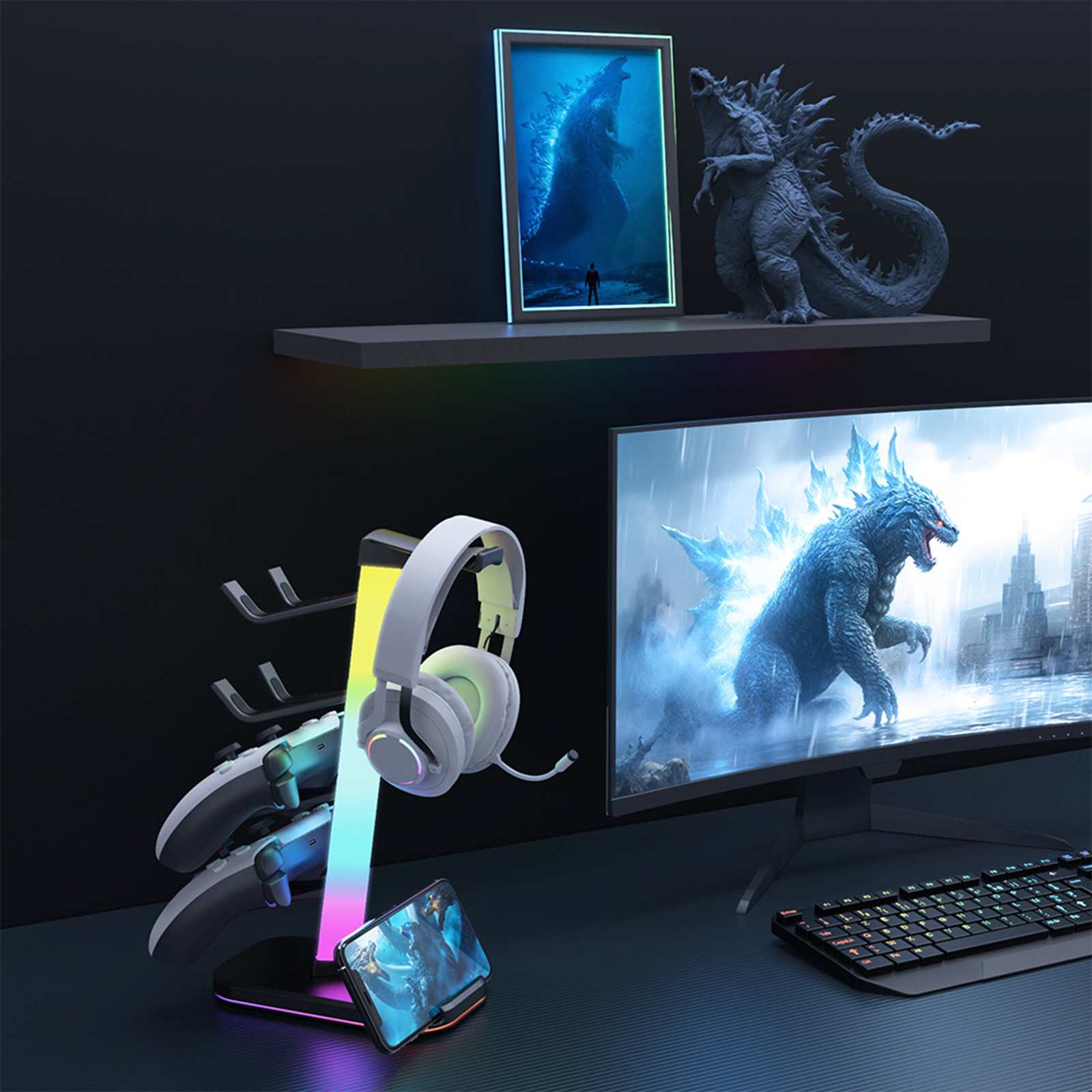 Gaming-Setup mit Godzilla-Monitor, Kopfhörern, Controllern und Handyhalterung. Regal mit Godzilla-Statue.