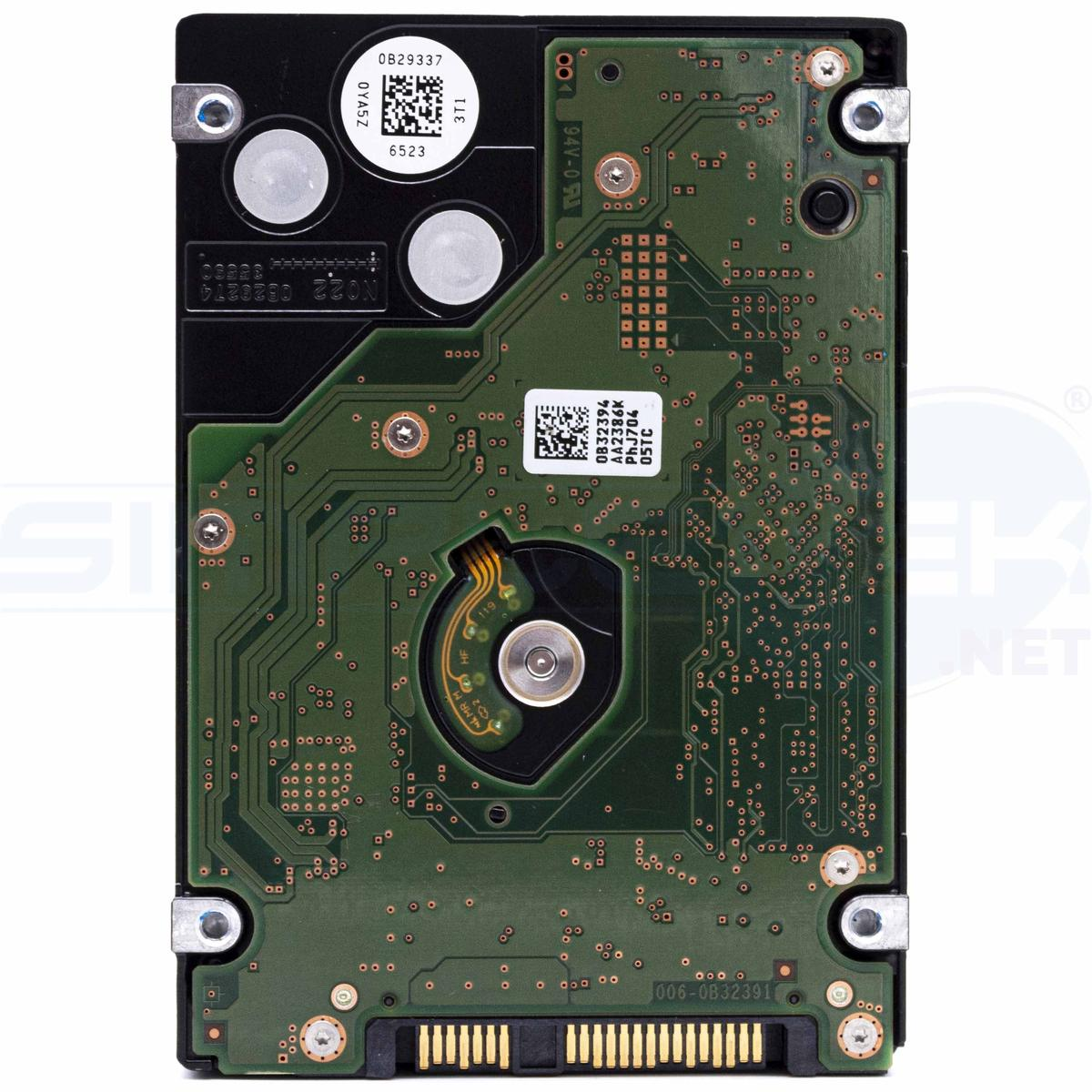 Primo piano di un disco rigido per computer. Circuito stampato verde con chip, involucro in metallo nero con etichette.