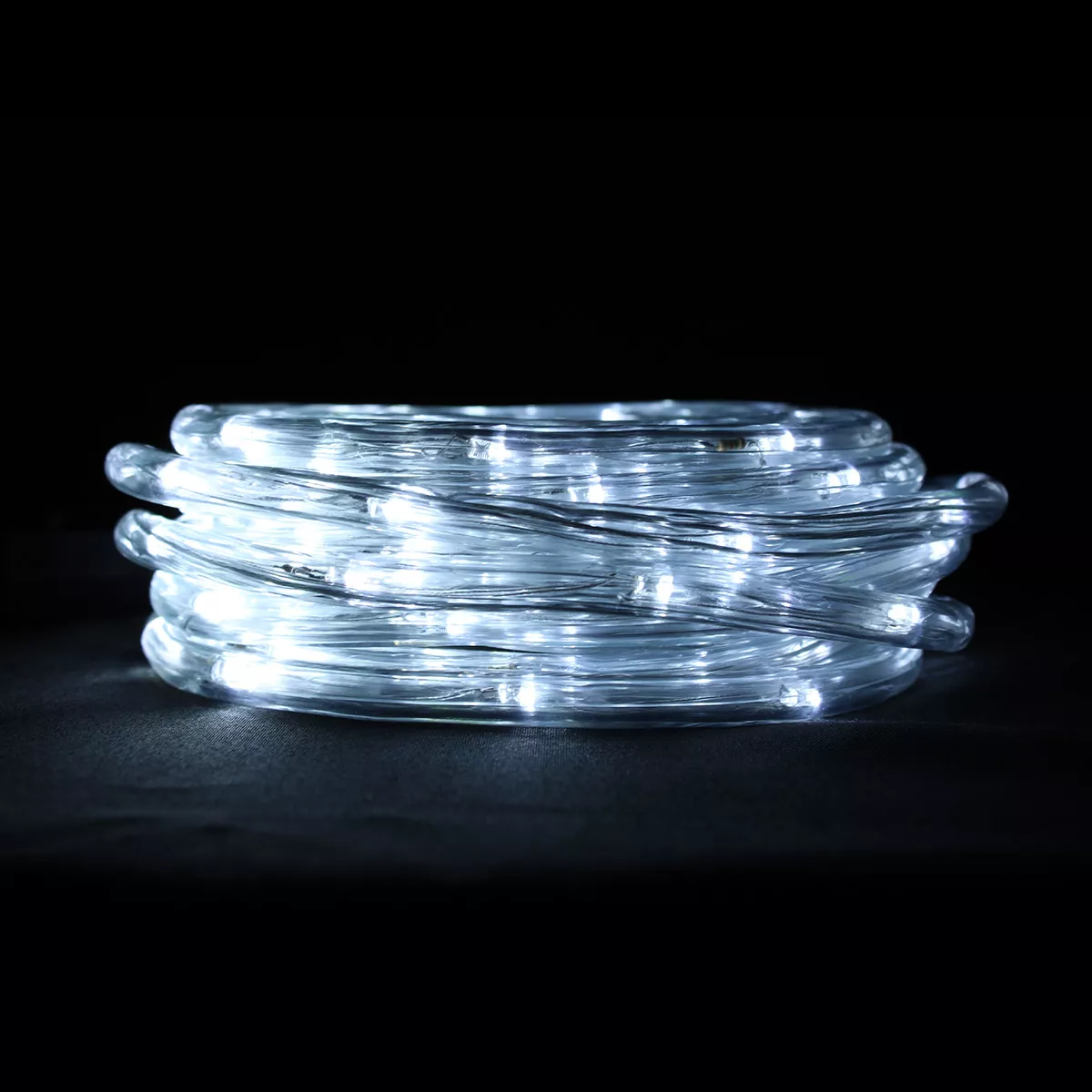 Aufgerollte Lichterketten mit weißen Lichtern. Der Hintergrund ist schwarz, die Lichter liegen auf einer dunklen Oberfläche.