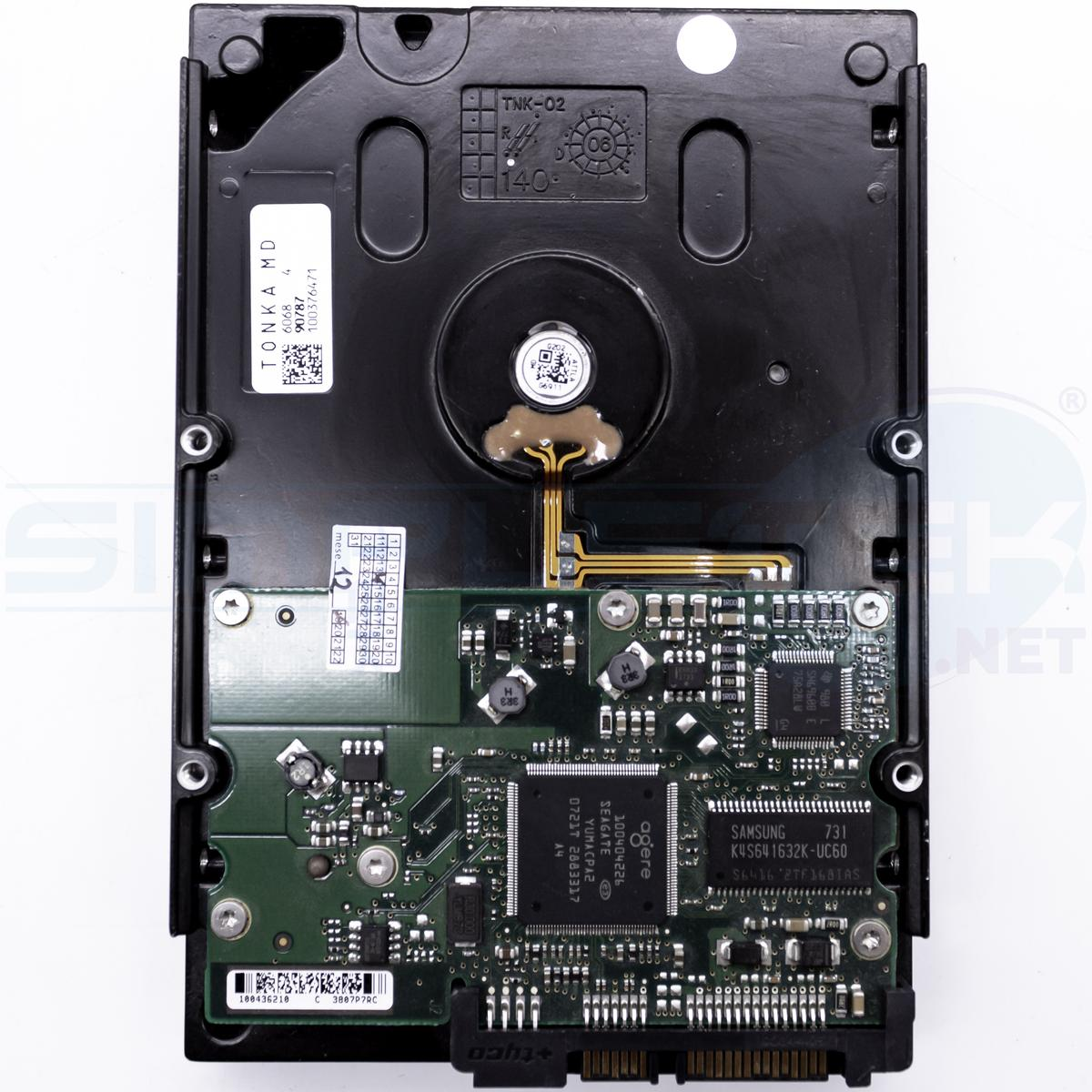 Un disco rigido, involucro nero, circuito stampato verde con chip, varie etichette e connettori. Vista dall'alto.