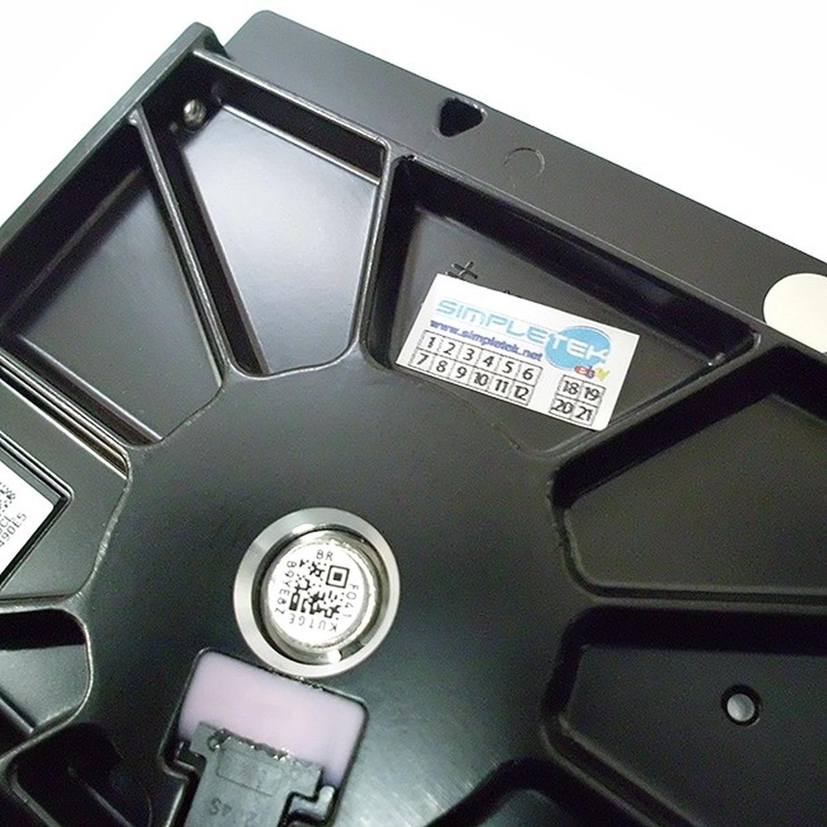 Primer plano de un componente negro de disco duro. Tiene una pegatina con números y un código QR, y una pieza circular plateada.