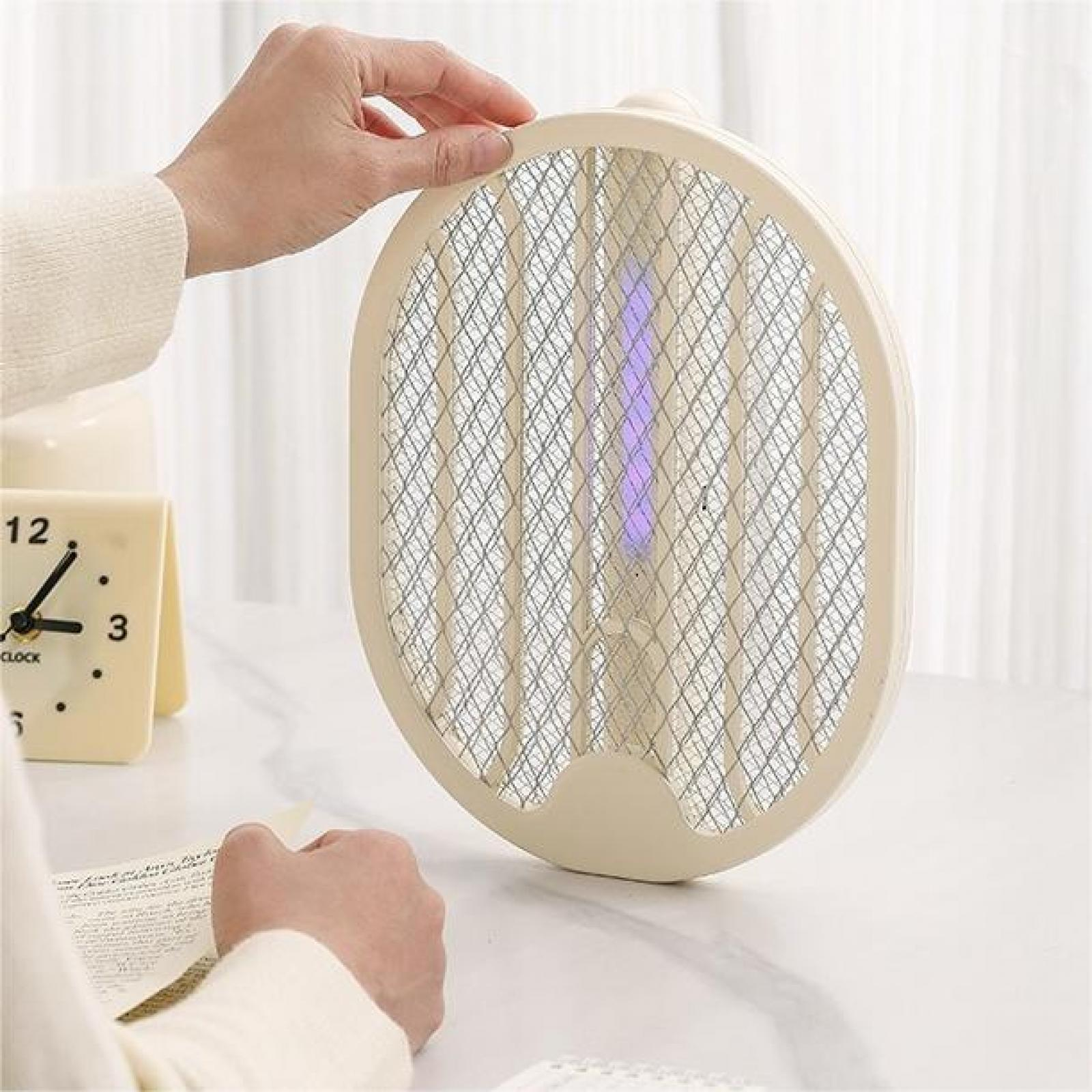 Eine Hand hält eine elektrische Fliegenklatsche. Eine Schreibtischuhr und Papier sind ebenfalls vorhanden. Der Schläger hat ein blaues Licht in der Mitte.